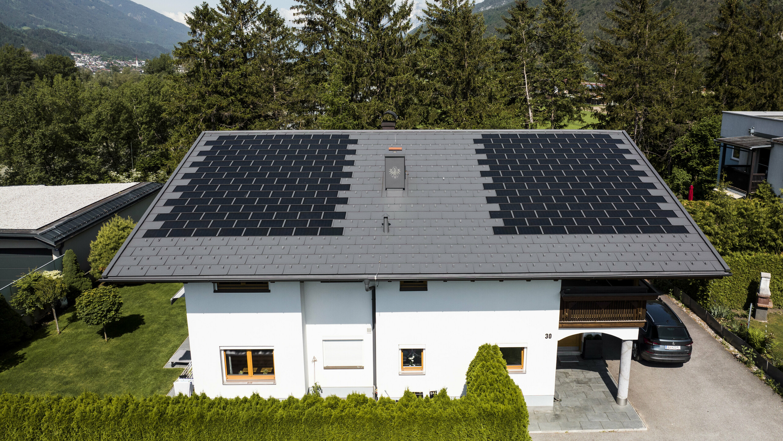 Nous pouvons apercevoir une maison familiale recouverte des petites tuiles solaires PREFA avec le R.16 dans la teinte P.10 gris sombre, dans un paysage rural.