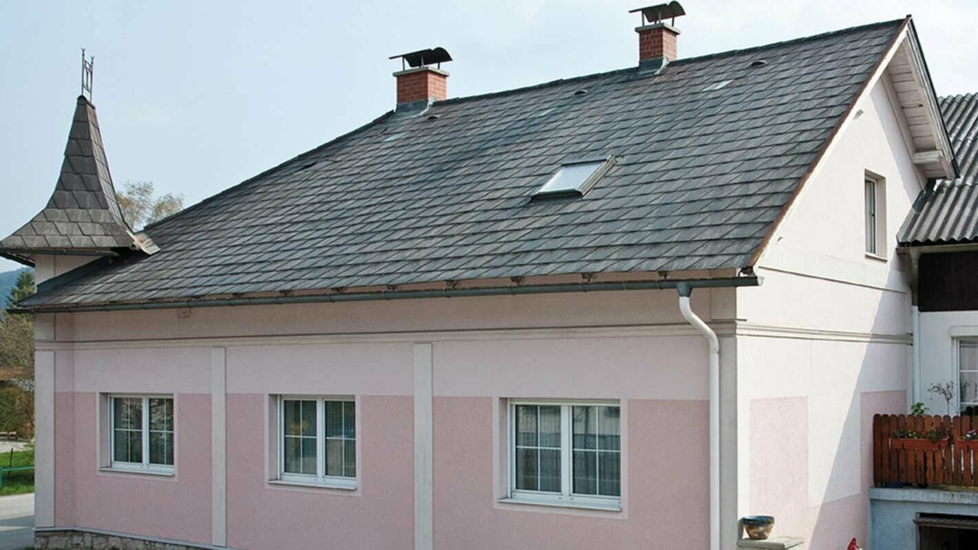 Maison avant la rénovation de toiture à l’aide de tuiles PREFA, en Autriche. Auparavant fibrociment Eternit et tourelle, façade rose