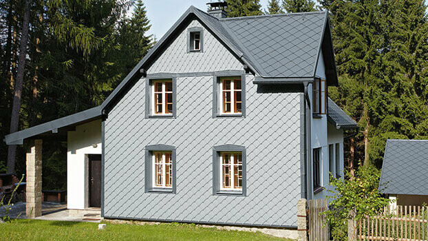 Maison individuelle avec système complet PREFA. La façade est recouverte de losanges de façade PREFA 29 couleur gris souris.