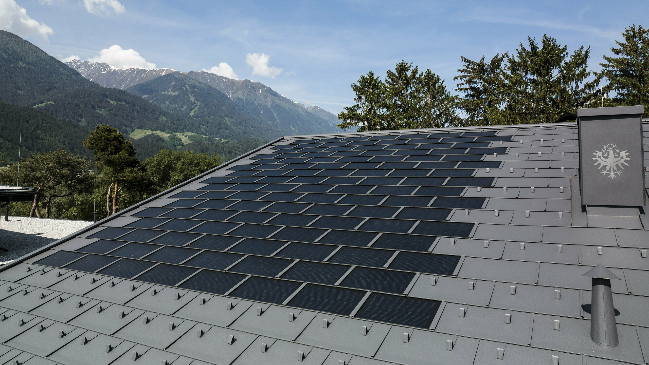 Photo de la toiture au Tyrol, recouverte avec la tuile solaire R.16 de PREFA couleur P.10 gris sombre