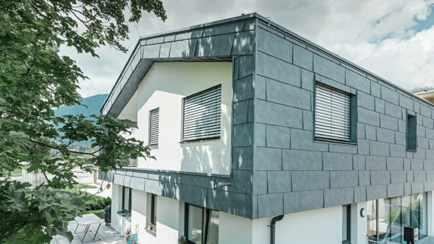 Premier étage d’un bâtiment d’habitation moderne revêtu de panneaux de façade FX.12 PREFA en aluminium de couleur gris pierre.