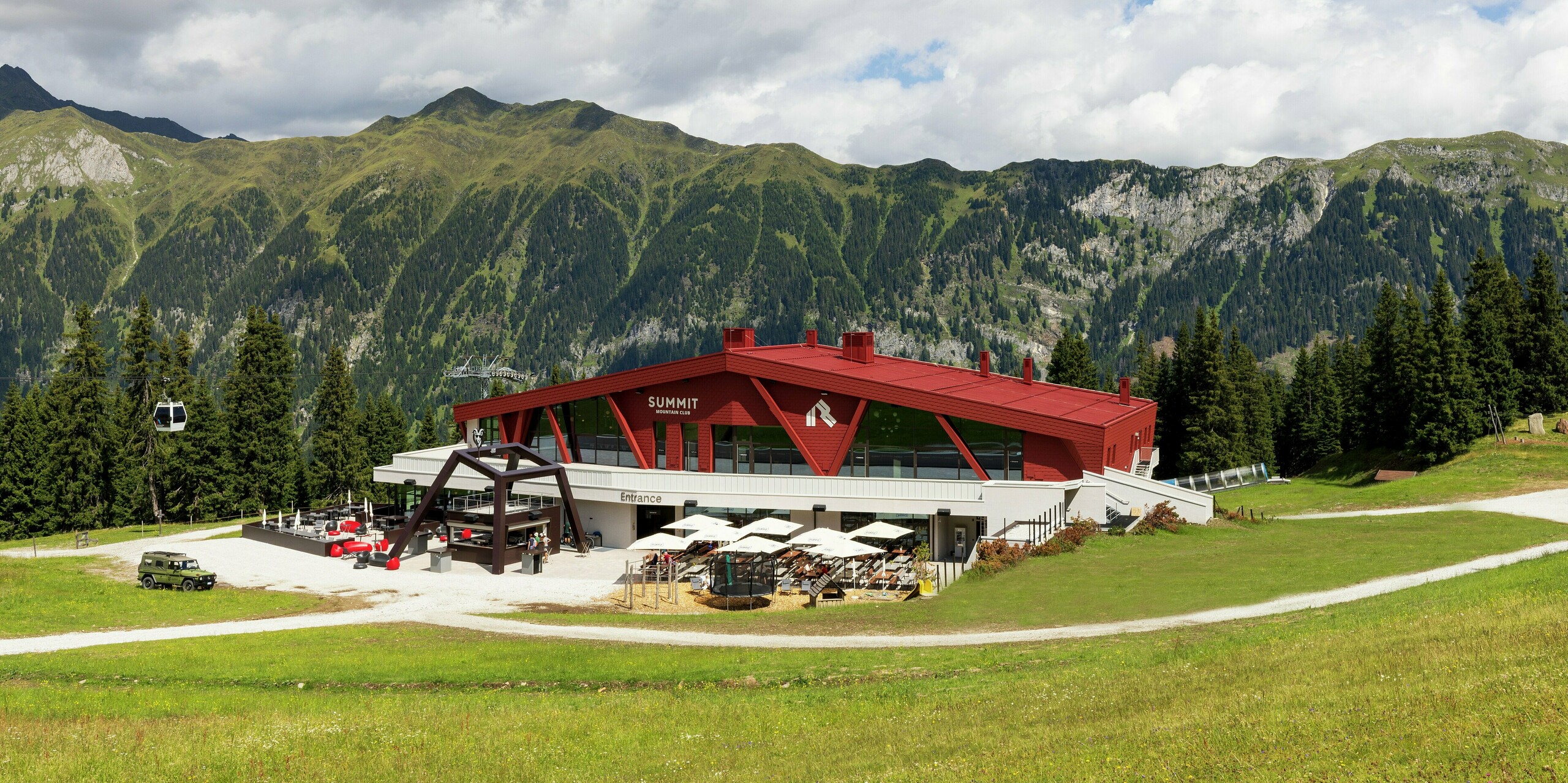 Le Summit Mountain Club de Ratschings impressionne par son architecture remarquable, son design original et le panorama montagneux à couper le souffle qui se dessine en arrière-plan. La toiture et la façade d'un rouge éclatant contrastent de façon saisissante avec le paysage alpin durant l'été. Le système de toiture PREFALZ, composé de panneaux robustes à joints debout, et les bardeaux PREFA de la façade garantissent une haute résistance aux conditions climatiques extrêmes telles que la neige, le verglas, le vent et le soleil. Ce matériau durable offre non seulement un rendu visuel exceptionnel, mais assure également une protection et une durabilité à long terme dans cette région montagneuse accidentée.