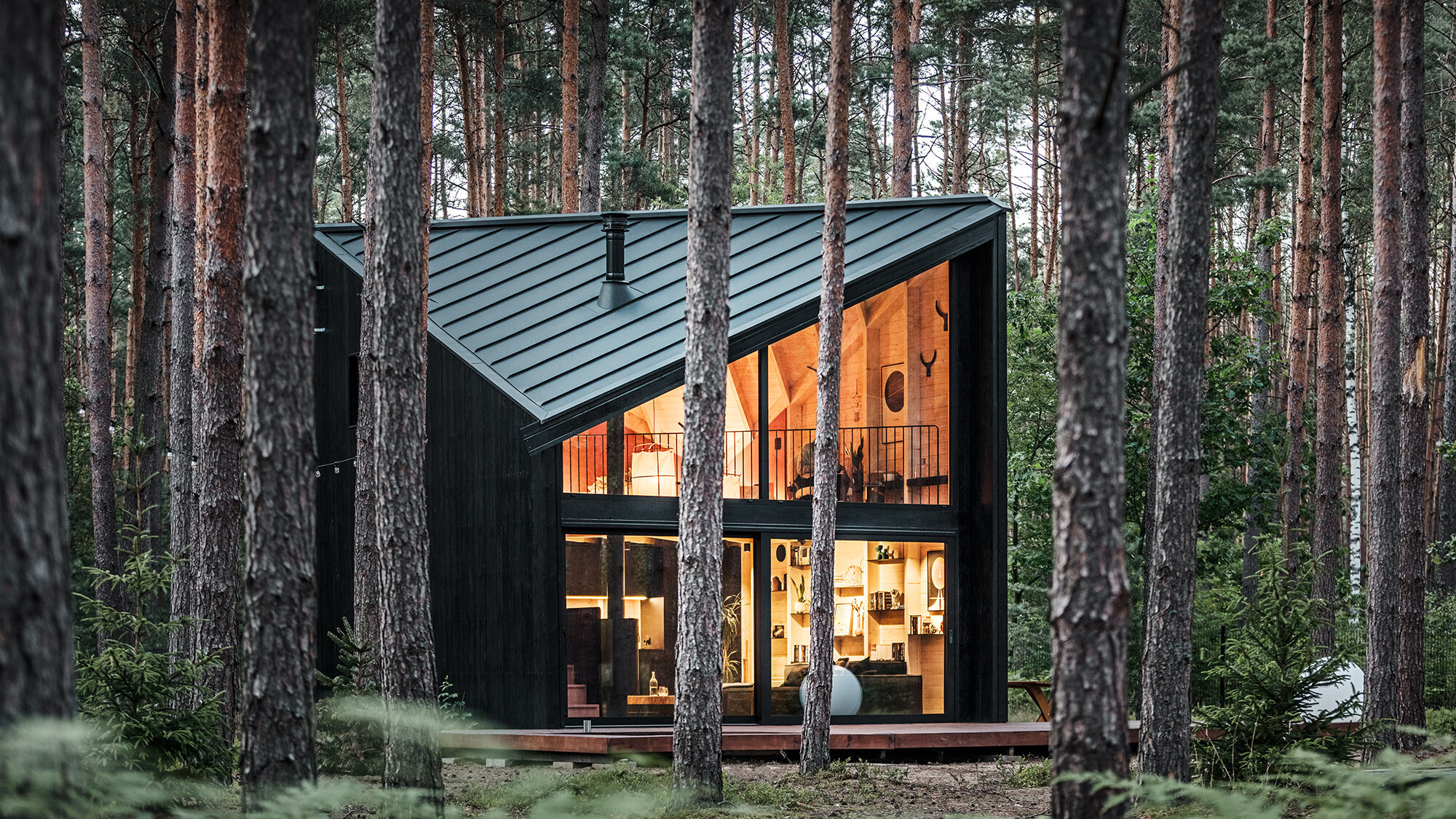 Vue latérale de la façade vitrée du bâtiment et de l'intérieur éclairé, inspiré par le style scandinave.