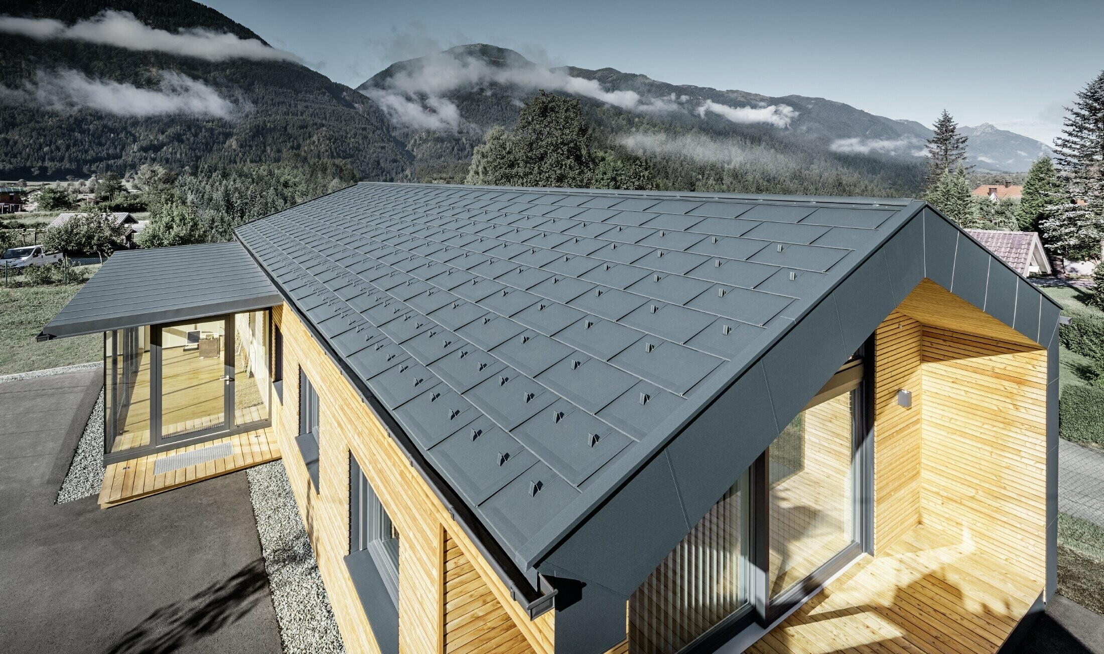Nouveau bâtiment administratif de Holzbau Faltheiner avec une façade en mélèze, de grandes baies vitrées et une toiture PREFA couleur anthracite.