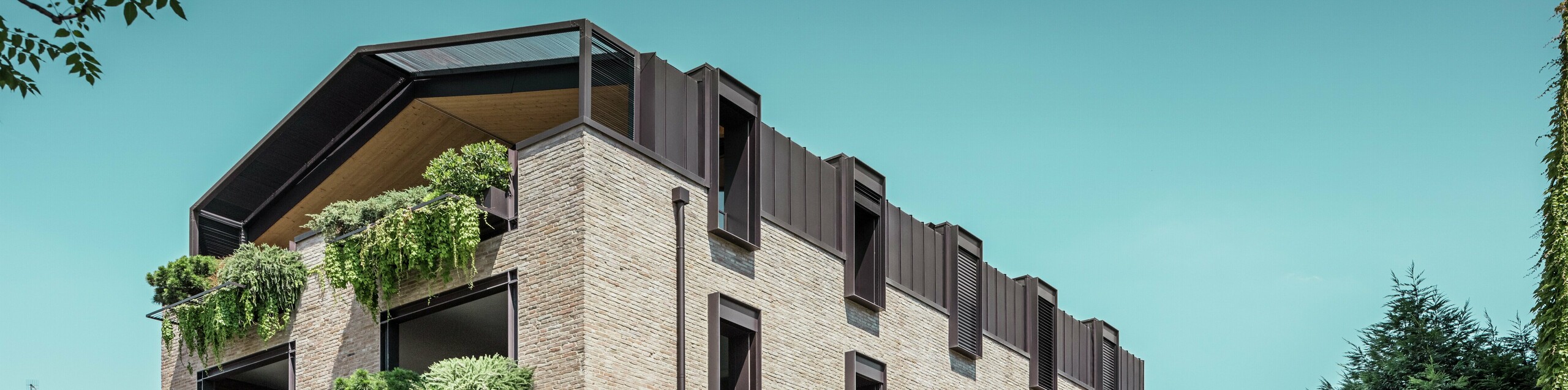 Immeuble résidentiel moderne en Italie avec toiture en aluminium PREFALZ en P.10 brun noisette, façade en briques et jardins suspendus – une architecture durable pour la rénovation de ce bâtiment.