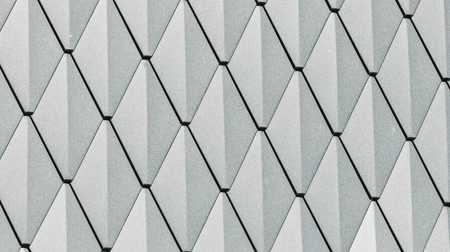 Lucarne trapézoïdale d'une maison individuelle à Mechernich, revêtue de petits losanges PREFA en P.10 anthracite. La toiture est recouverte de DS.19 PREFA de la même couleur. Le revêtement en aluminium de haute qualité garantit une résistance aux intempéries et un aspect moderne et esthétique.