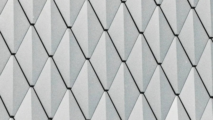Lucarne trapézoïdale d'une maison individuelle à Mechernich, revêtue de petits losanges PREFA en P.10 anthracite. La toiture est recouverte de DS.19 PREFA de la même couleur. Le revêtement en aluminium de haute qualité garantit une résistance aux intempéries et un aspect moderne et esthétique.