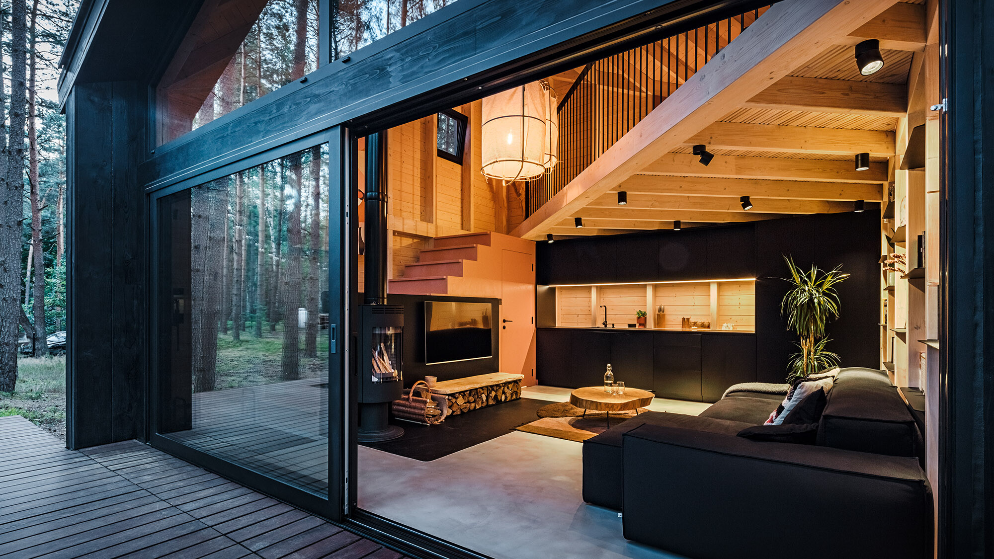 Vue latérale d'une maison de vacances avec un toit en PREFALZ en pente. La nature environnante se reflète dans la zone vitrée.