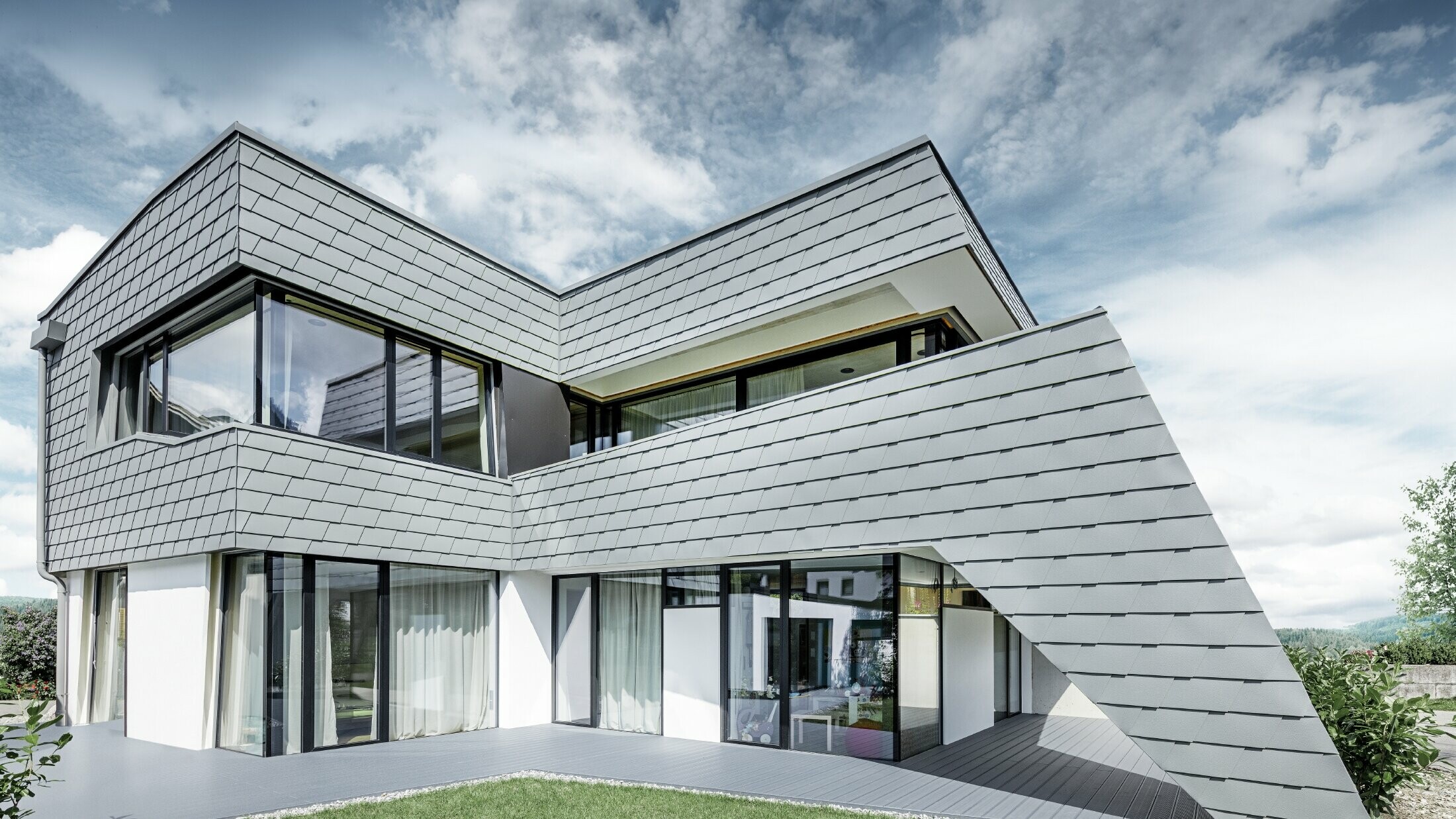 Maison individuelle moderne au toit plat avec de grandes baies vitrées — Façade réalisée avec des bardeaux PREFA en aluminium de couleur gris souris