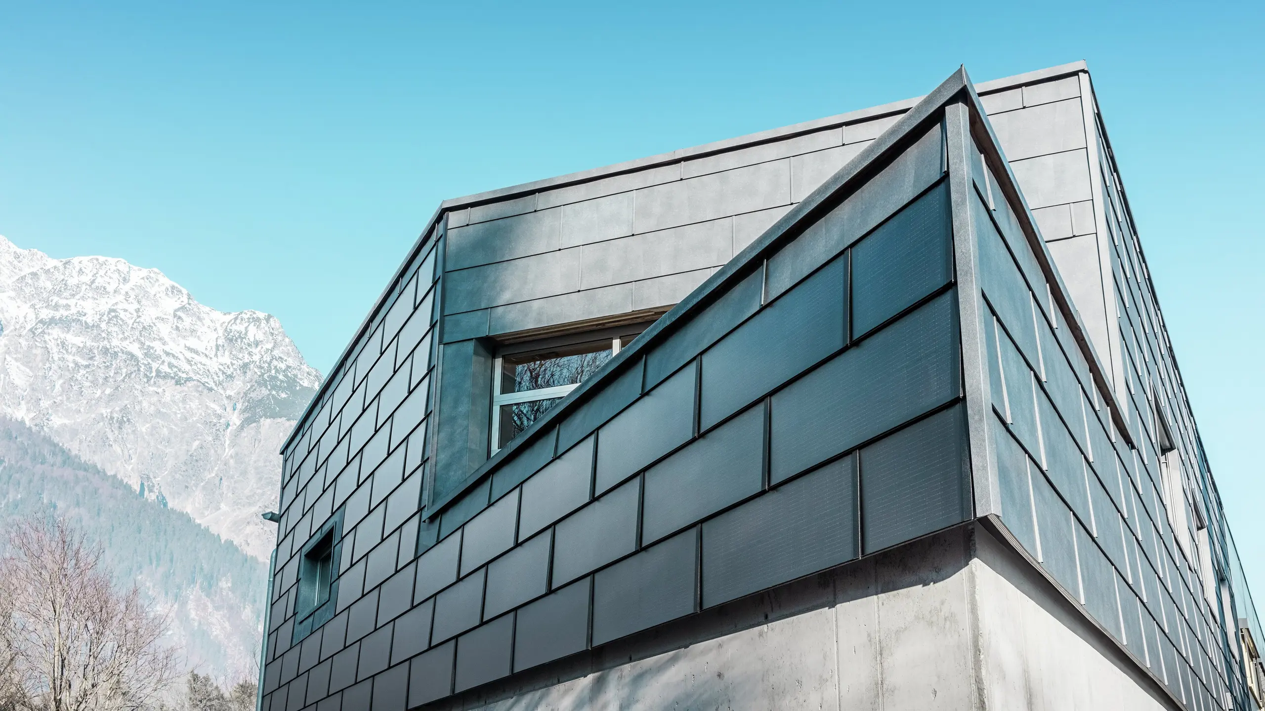 Façade moderne avec la tuile solaire PREFA : les panneaux en aluminium durables avec photovoltaïque intégré produisent de l'électricité et s'intègrent harmonieusement dans le design architectural.