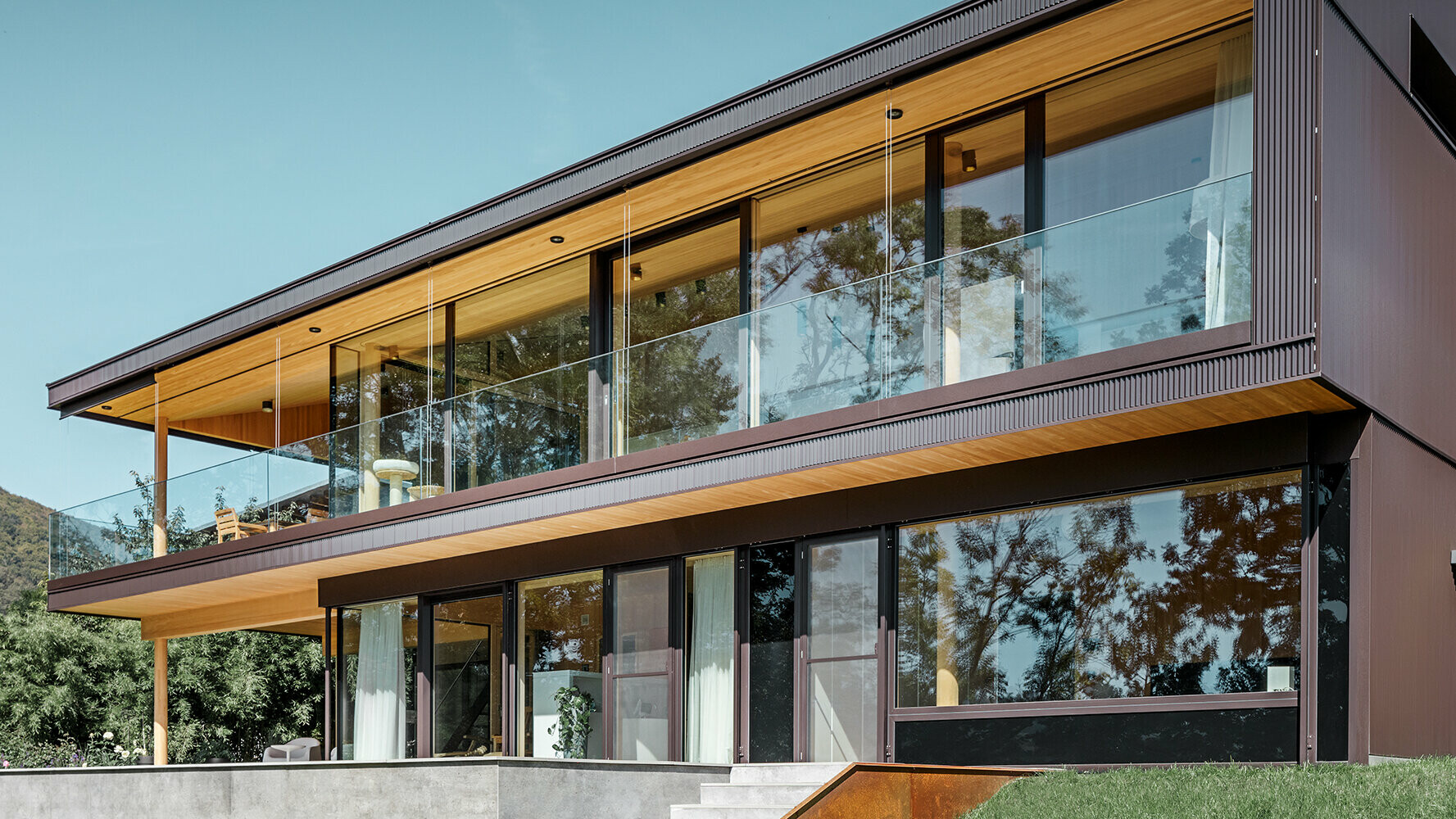 Construction neuve d'une maison individuelle avec une importante surface vitrée et une façade en aluminium dans la teinte brun