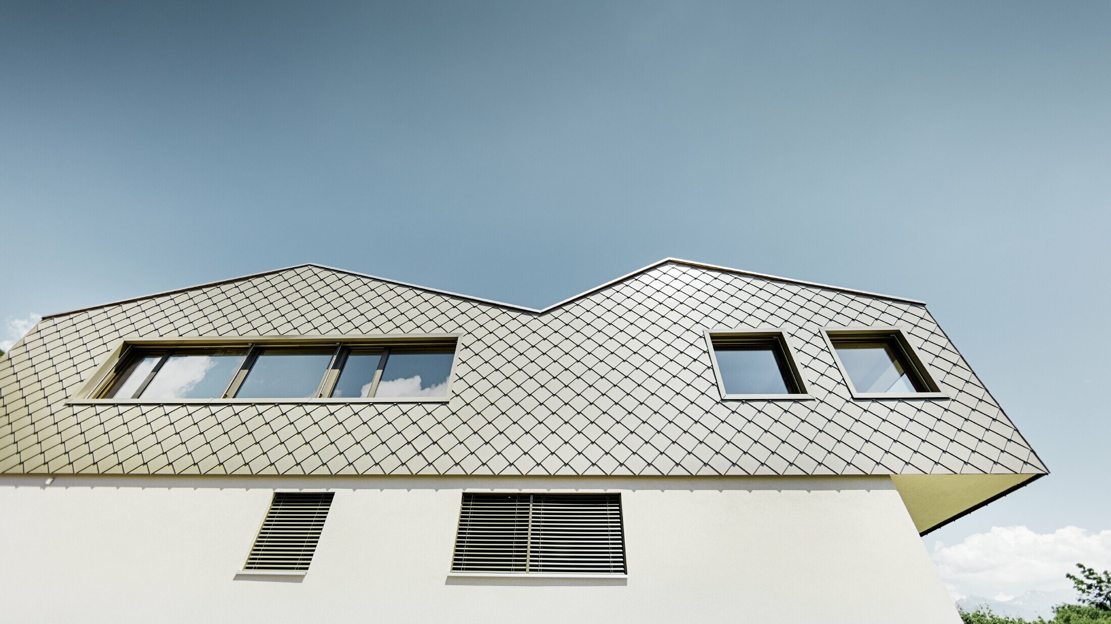 Maison individuelle moderne au milieu des vignobles de la vallée du Rhône avec 4 toits différents et galerie ouverte avec une façade en losanges couleur bronze