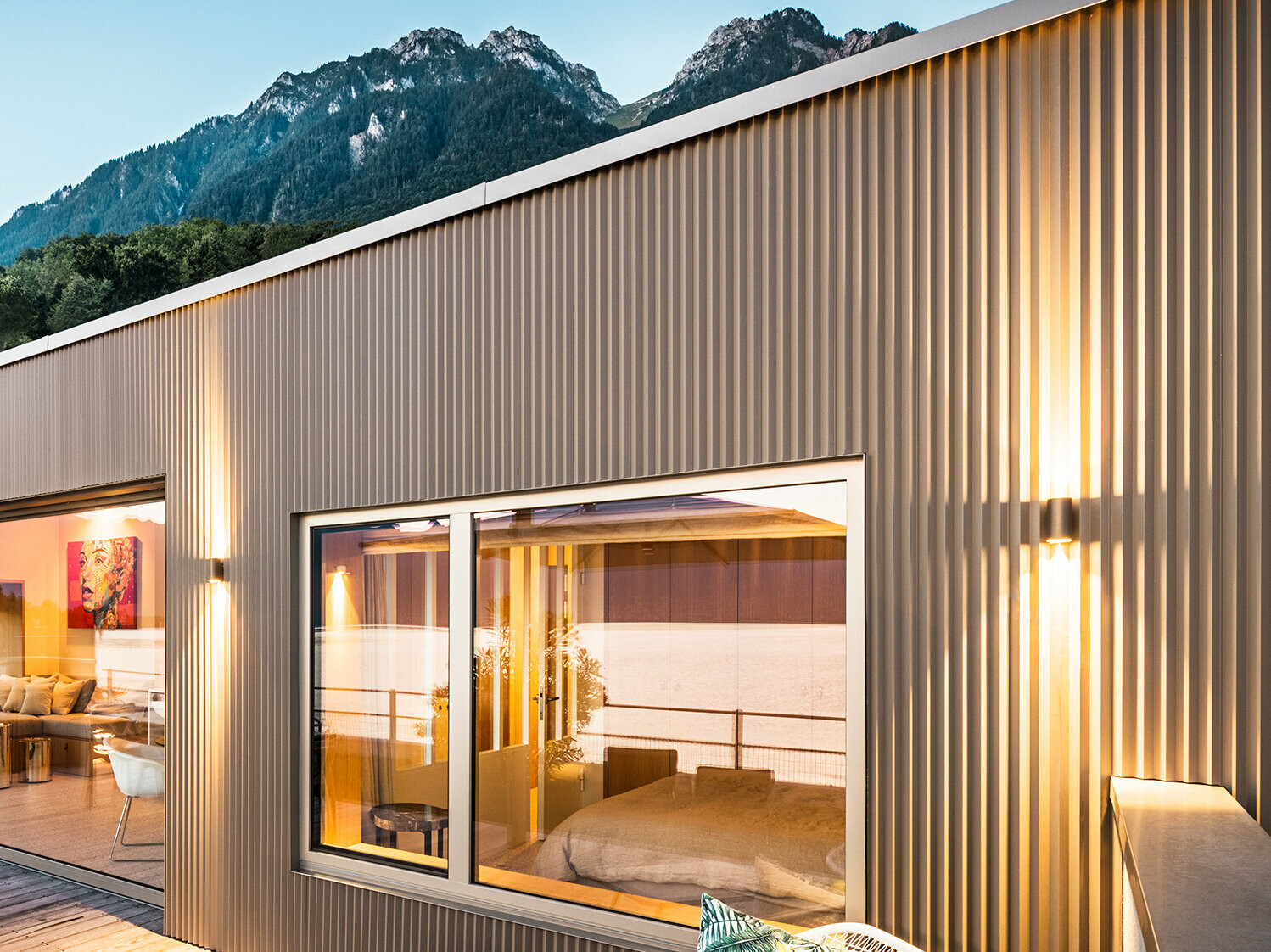 Vue sur la terrasse et une partie de l'intérieur du bâtiment le soir.