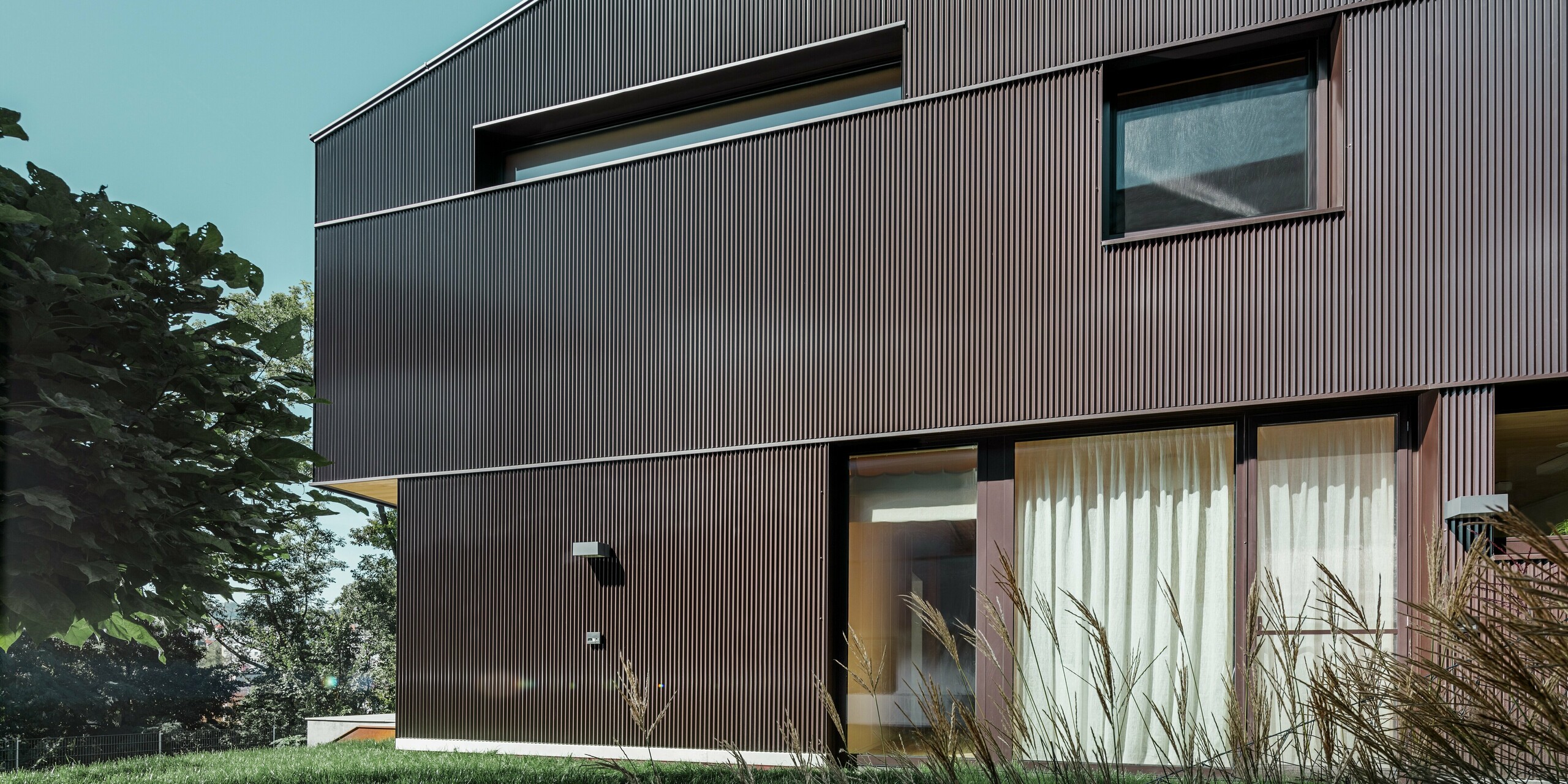 Maison individuelle moderne avec un habillage de façade en profil triangle PREFA couleur brun.