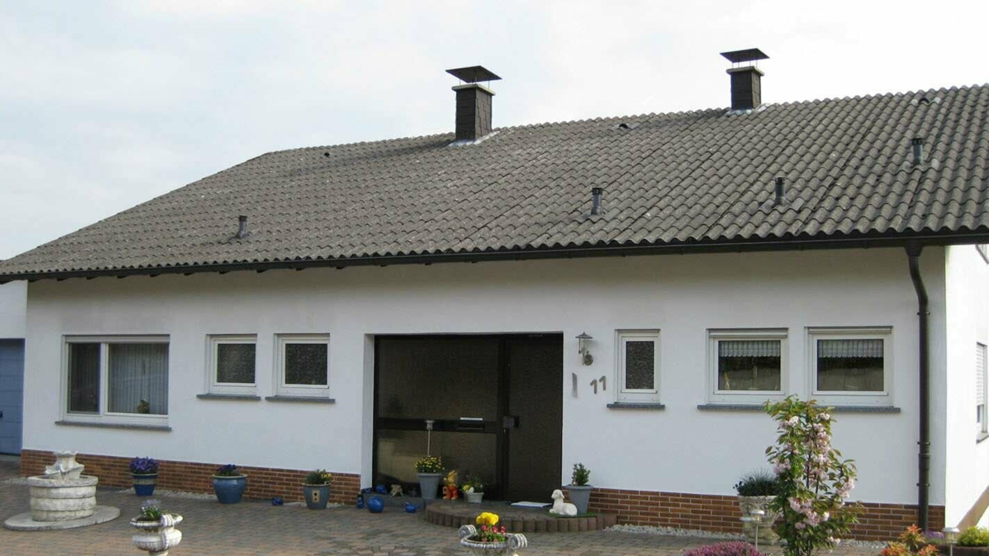 Maison individuelle avec fibrociment ondulé avant la rénovation de toiture à l’aide de tuiles PREFA