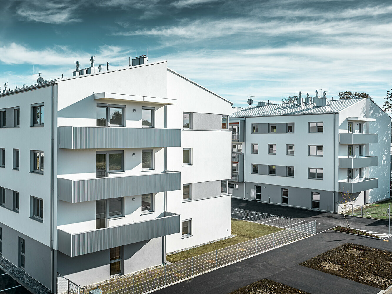 Complexe résidentiel moderne avec façade blanche et balcons en profil triangle PREFA couleur argent métallisé