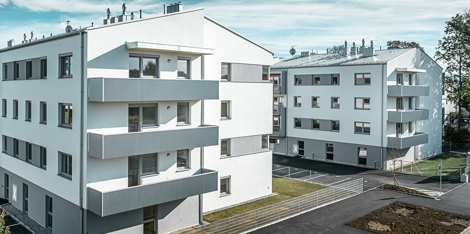 Complexe résidentiel moderne avec façade blanche et balcons en profil triangle  PREFA couleur argent métallisé