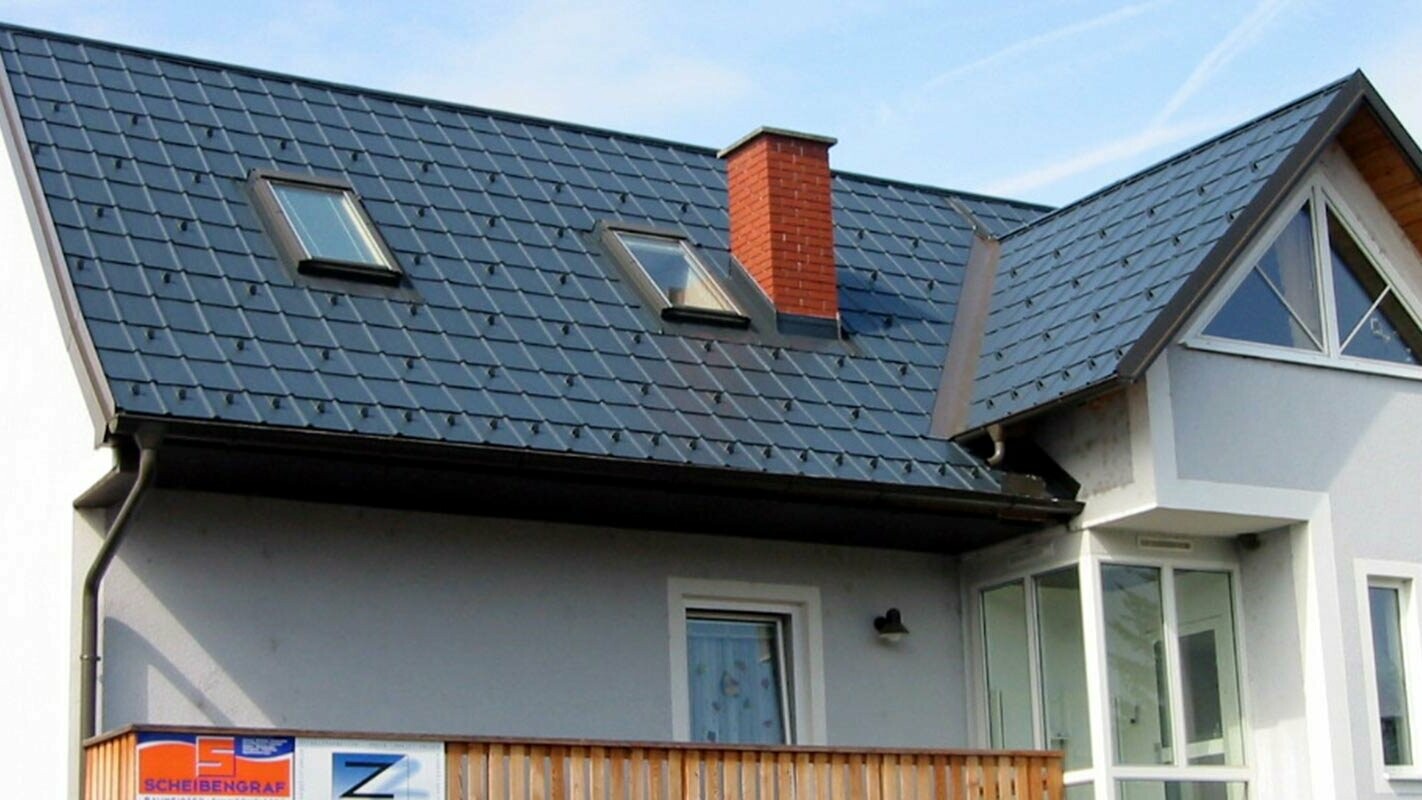 Maison individuelle avec toit à deux pans et façade bleue, toit récemment rénové par PREFA