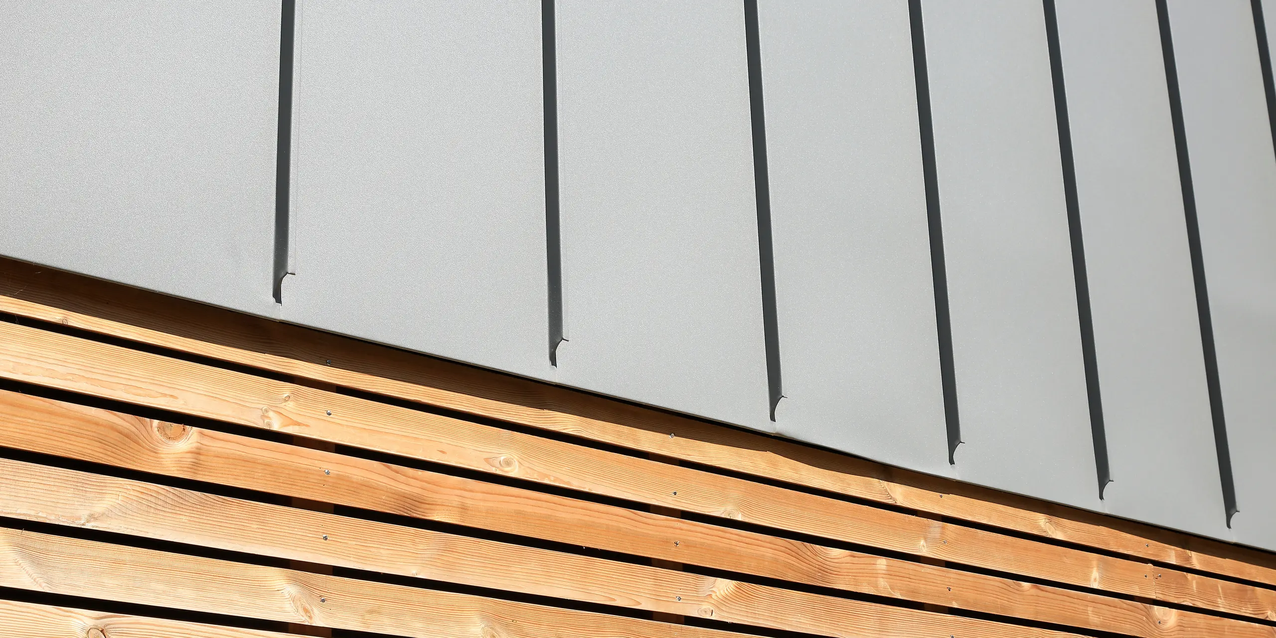 Le joint debout PREFALZ en gris souris s'étend sur les façades et les toits à pignon d'un lotissement mitoyen à Mundolsheim. Les coques uniformes du bâtiment en aluminium créent une image globale harmonieuse.