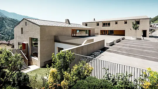 Le centre éducatif de Riffian se distingue par deux volumes architecturaux marquants, revêtus de losanges de toiture PREFA 44 × 44 en coloris Bronze P.10, qui se détachent sur un décor alpin. Ce revêtement en aluminium, réalisé avec précision, souligne la netteté des lignes et assure une protection durable contre les intempéries ; il unifie le jardin d’enfants, l’école primaire et la cour ensoleillée pour former un ensemble architectural moderne et harmonieux.