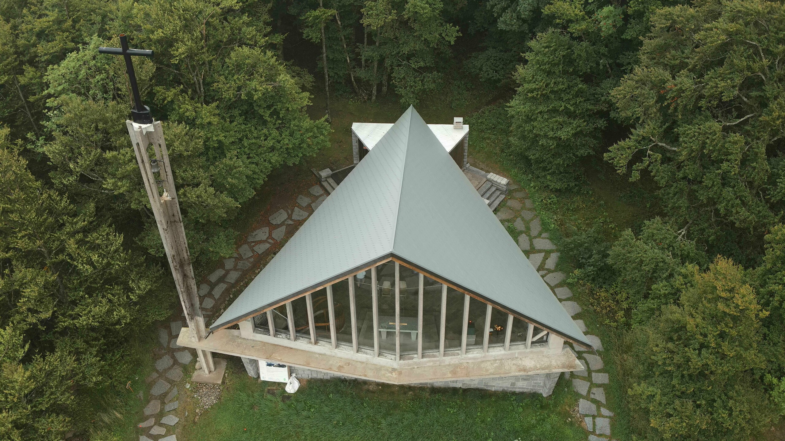 Prise de vue par drone de la toiture de la chapelle du Col de la Schlucht rénovée grâce aux bardeaux en aluminium PREFA dans la teinte P.10 gris souris. On aperçoit également les larges baies vitrées sur le devant de la chapelle.