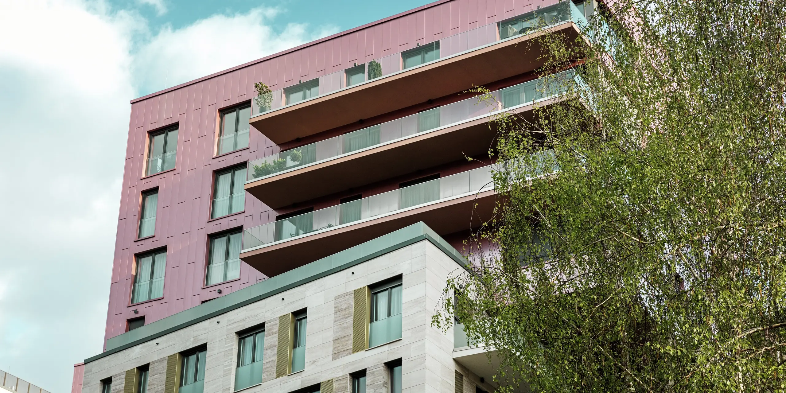 La partie supérieure du complexe résidentiel « Grand Corvin » à Budapest est dotée d'une remarquable façade en Siding PREFA en aluminium, posée verticalement et d'une couleur saumon métallisé brossé. Ces panneaux de façade de haute qualité confèrent au bâtiment une allure moderne et élégante et apportent une touche architecturale remarquable au quartier Corvin en pleine renaissance.