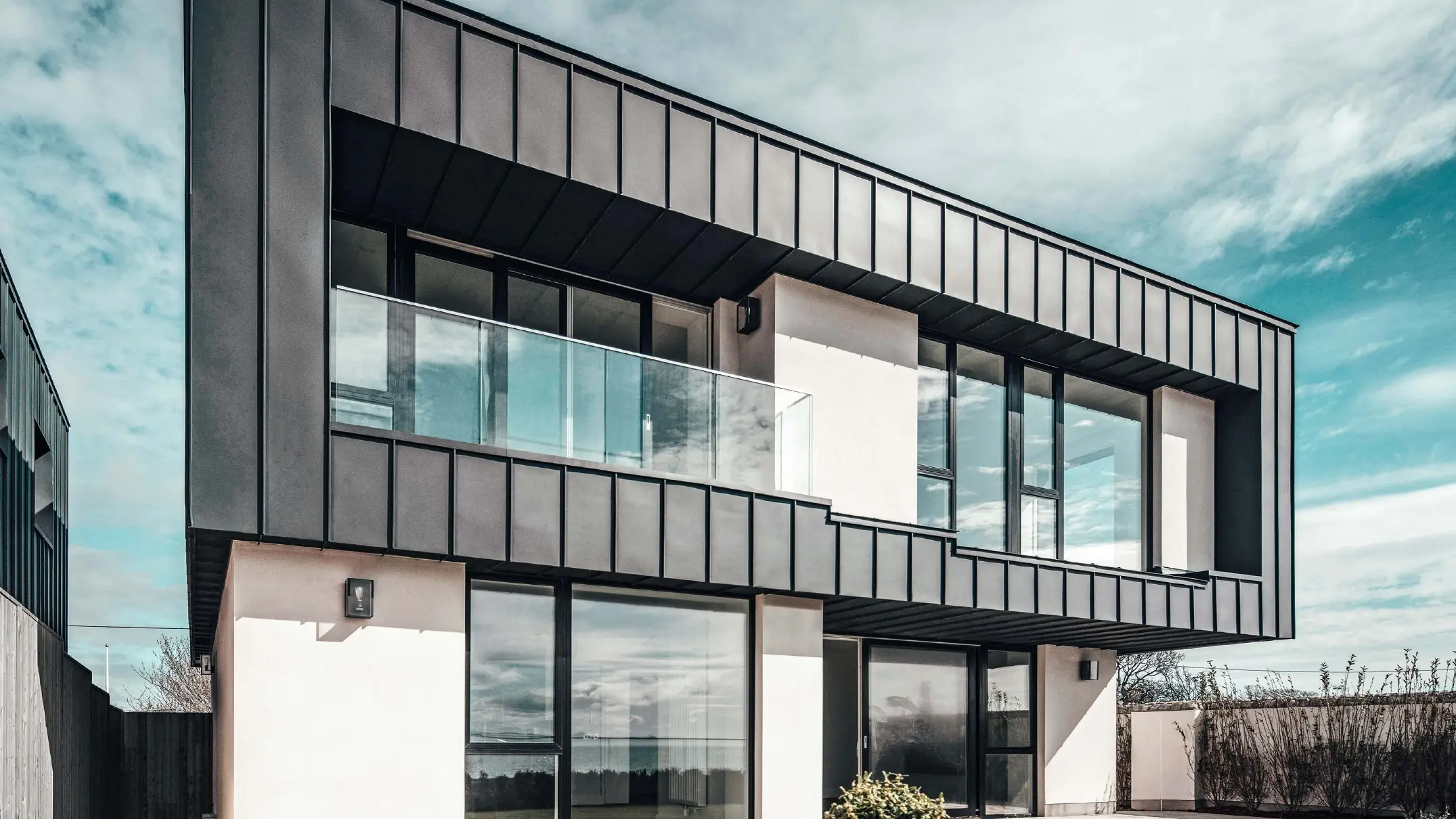Maison mitoyenne avec toit plat, la façade à l'étage supérieur a été conçue à l'aide d'une façade à joint debout en PREFALZ couleur anthracite.