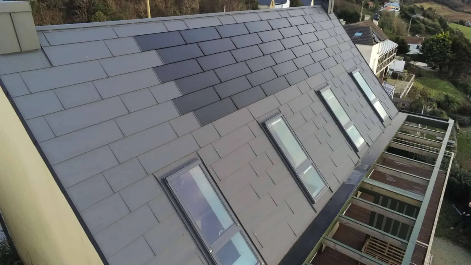 Vue latérale depuis la toiture de cette maison individuelle située face à la mer, à Les Pieux. Elle a récemment été rénovée avec les produits de toiture PREFA : panneaux FX.12 et tuile solaire PREFA dans la teinte P.10 gris sombre.