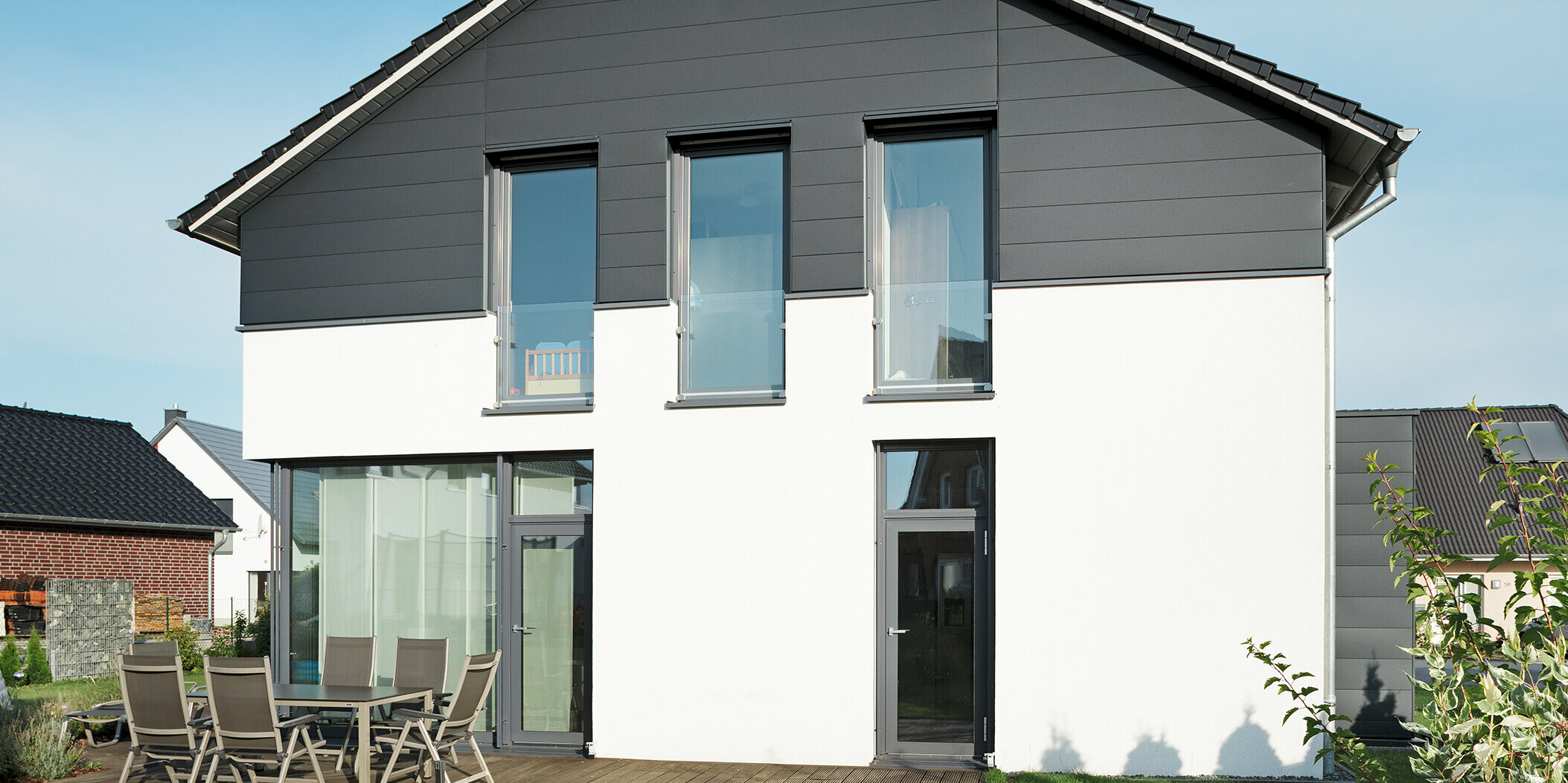 Stilvolle Giebelseite eines Einfamilienhauses in Isenbüttel, verkleidet mit langlebigen PREFA Fassadenpaneelen in P.10 Anthrazit für ein zeitgemäßes Design. Die hochwertige Blechfassade und die Hochkantfenster fügen sich harmonisch in die moderne Architektur ein.