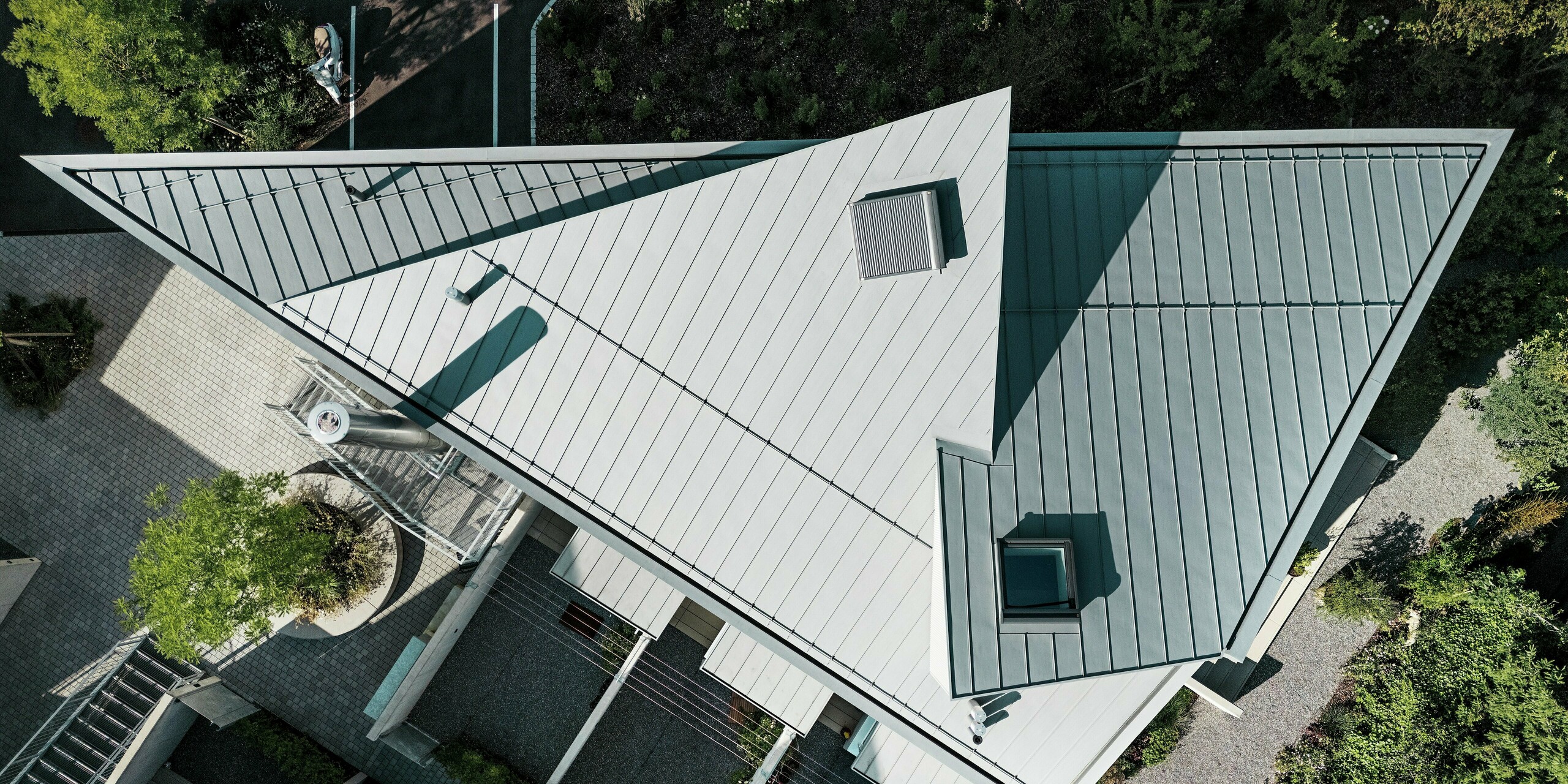Vue de dessus de la toiture PREFALZ à joints debout, d'un gris quartz remarquable, d'une tiny house en Suisse. La précision de sa construction souligne la géométrie exceptionnelle du bâtiment. PREFALZ séduit par sa flexibilité de conception, son extrême résistance aux intempéries et sa surface en aluminium de haute qualité, pour des solutions de toiture durables.