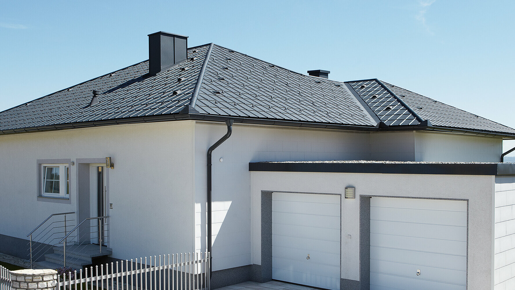 Bungalow dont le toit à croupes a été rénové avec des tuiles PREFA couleur anthracite. Un garage double se situe juste à côté.