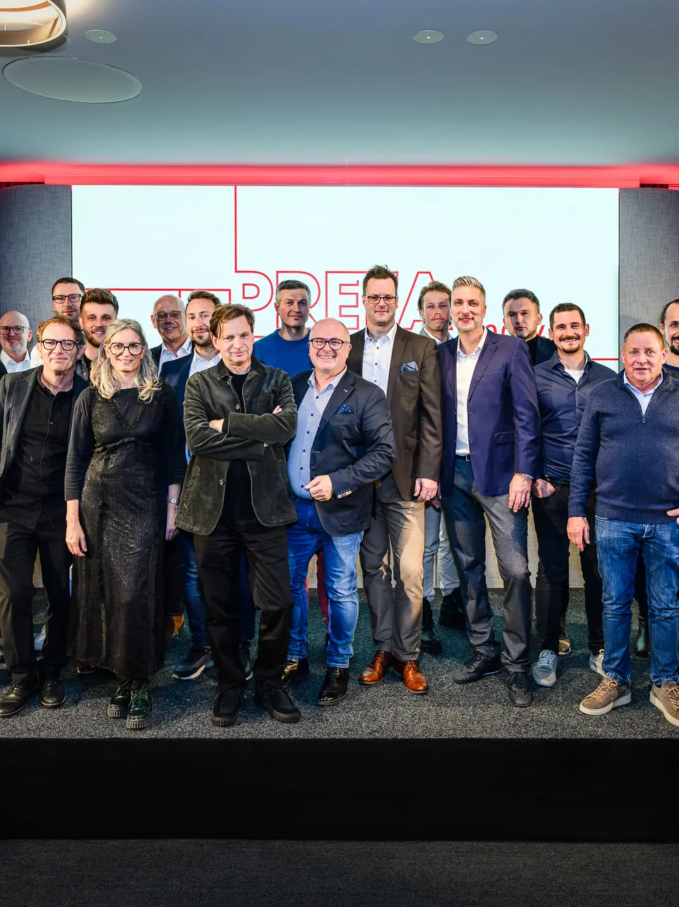 Photo de groupe des architectes, urbanistes et fabricants sur la scène de la présentation PREFARENZEN 2026 au k47.wien – un symbole fort de communauté, de créativité et d'architecture d'avenir. Devant le logo PREFARENZEN illuminé se tiennent les concepteurs des projets impressionnants intégrant l'aluminium PREFA. Cette scène reflète la fierté, l'innovation et la collaboration. Les produits PREFA offrent des solutions durables et résistantes aux intempéries, au design soigné – idéales pour les concepts architecturaux modernes. Une soirée inspirante, riche en échanges, en visions et en partenariats solides.