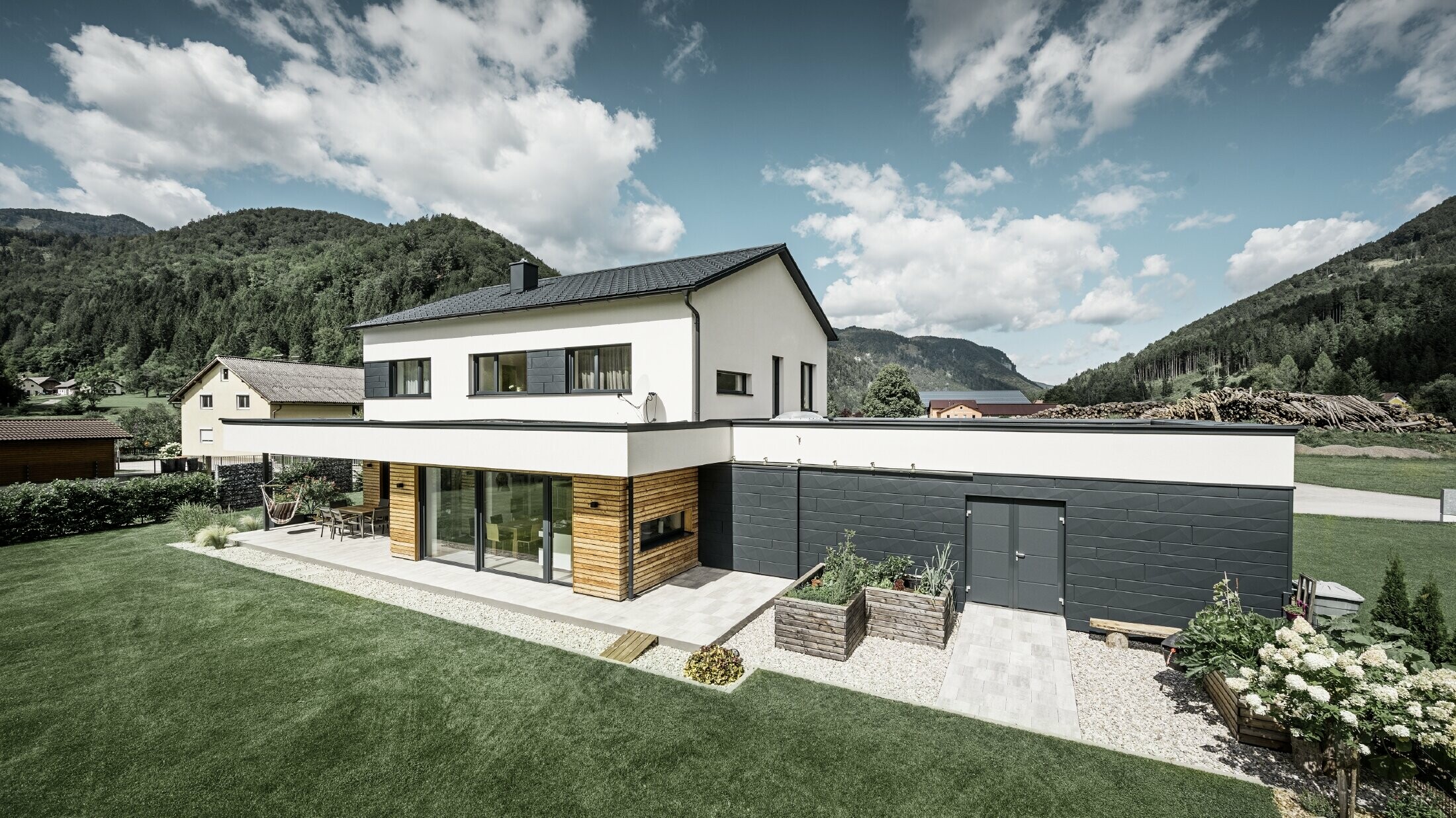 Maison individuelle moderne dans un environnement rural, avec les produits de toiture et de façade PREFA. 