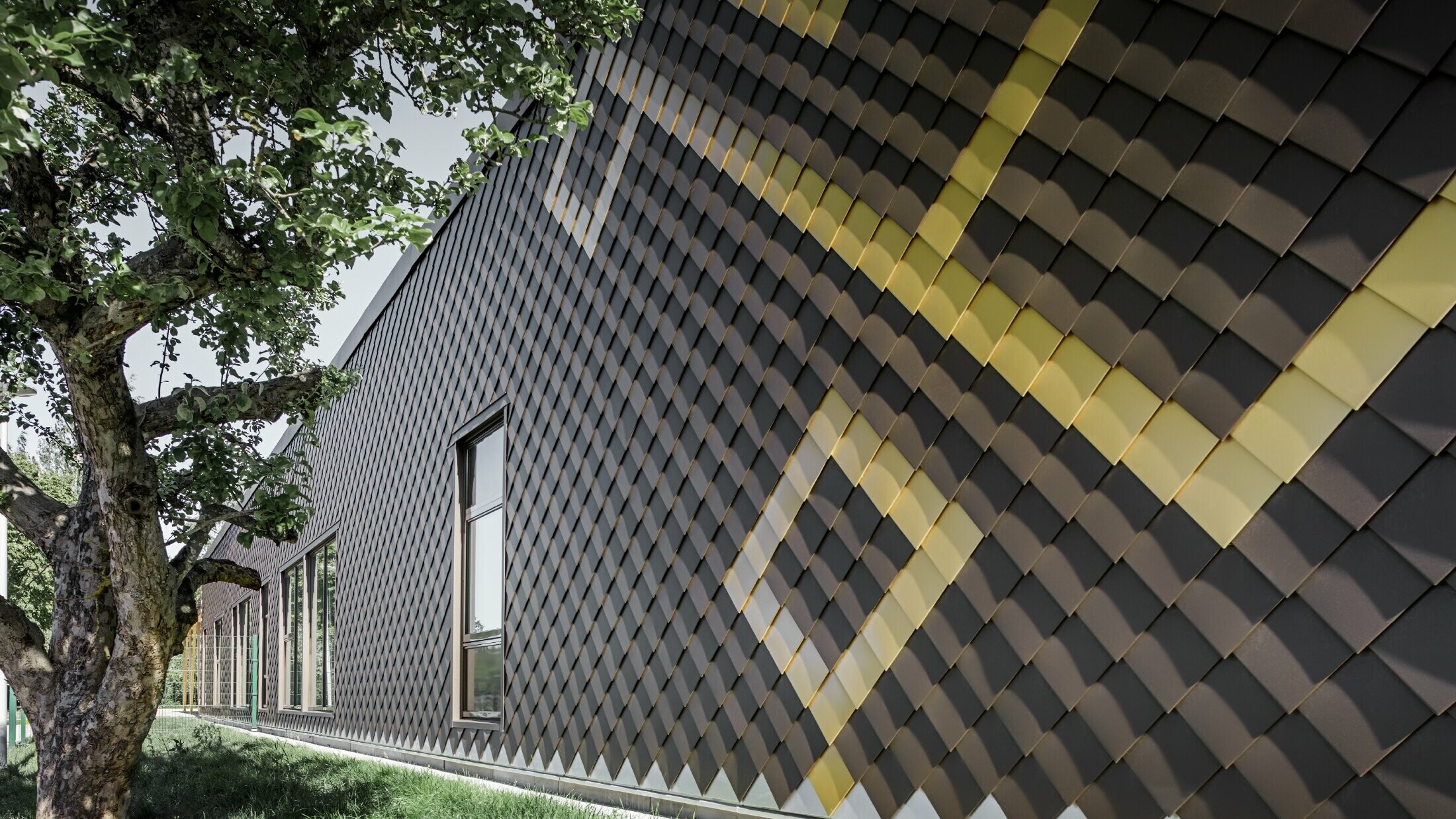 La façade de l’école maternelle de Stockholm a été habillée avec des losanges de façade de PREFA. Les couleurs brun et or maya viennent parer la façade extérieure d’un joli motif.