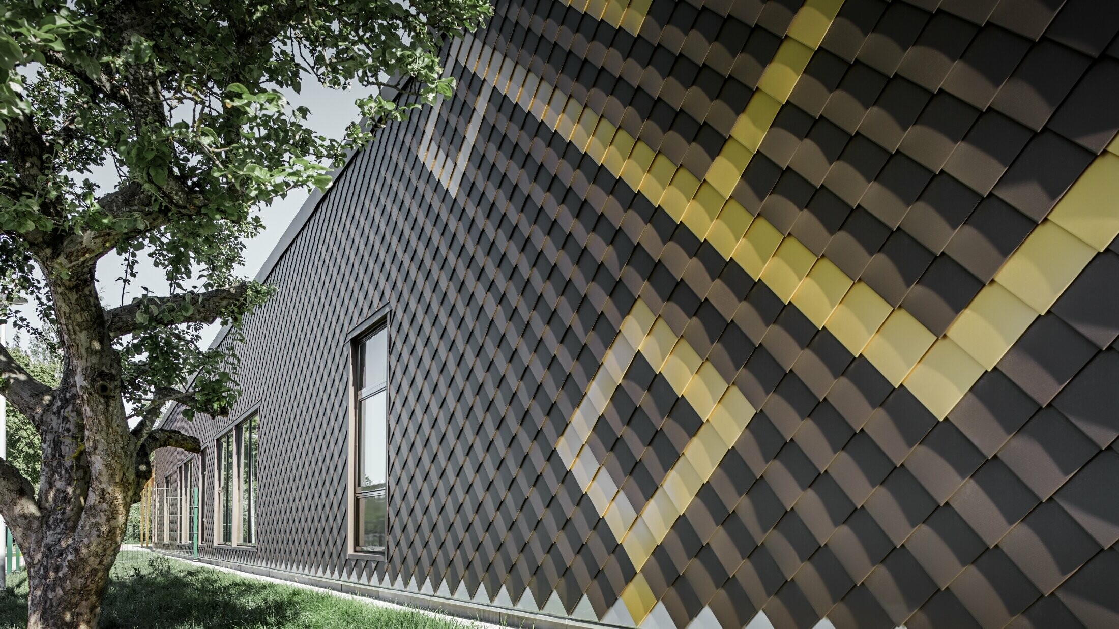 La façade de l’école maternelle de Stockholm a été habillée avec des losanges de façade de PREFA. Les couleurs brun et or maya viennent parer la façade extérieure d’un joli motif.