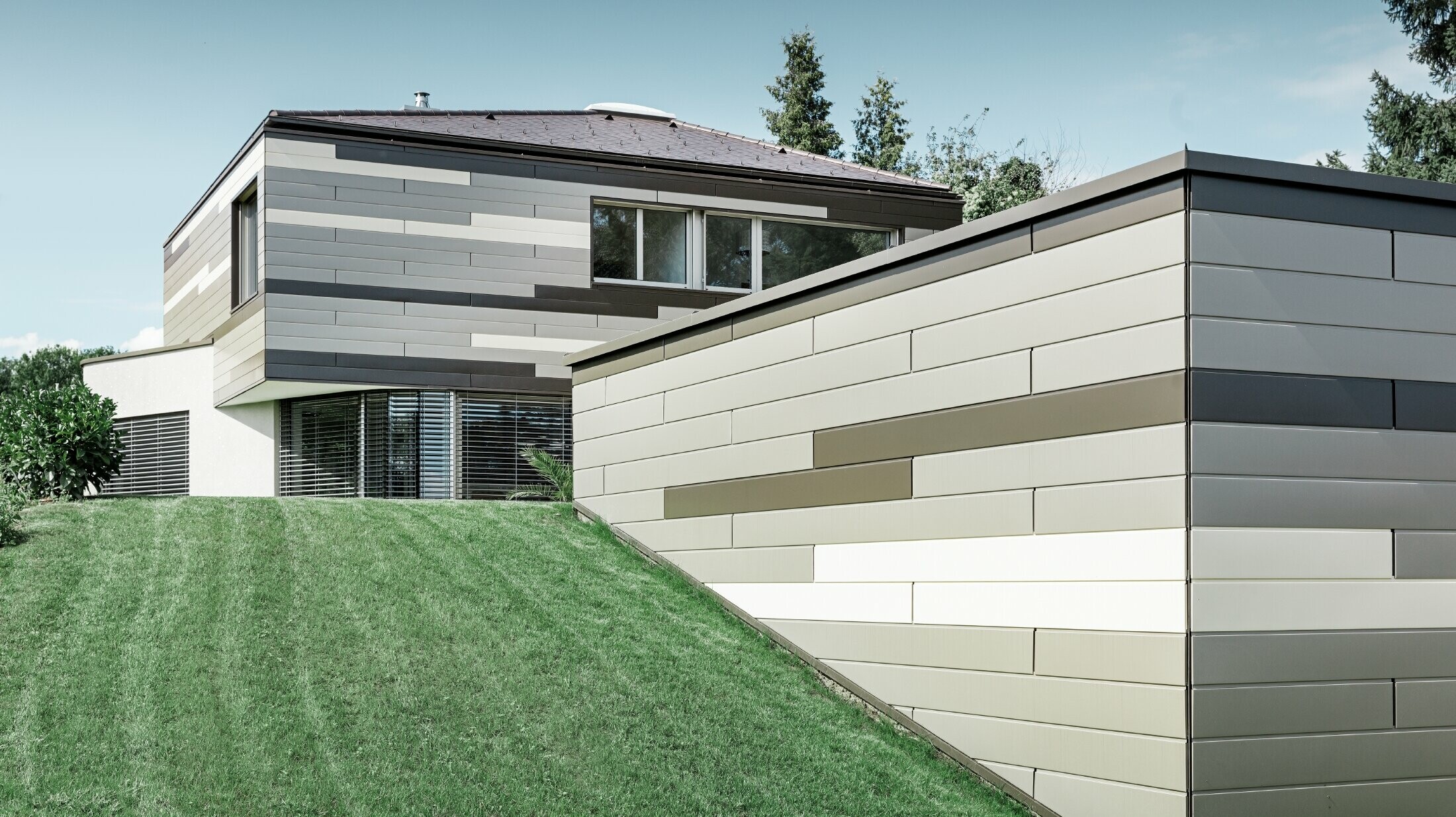 Maison individuelle moderne au toit plat avec terrasse couverte — Façade en aluminium au caractère très individuel réalisée avec des sidings PREFA de trois couleurs différentes (brun, bronze et ivoire clair)