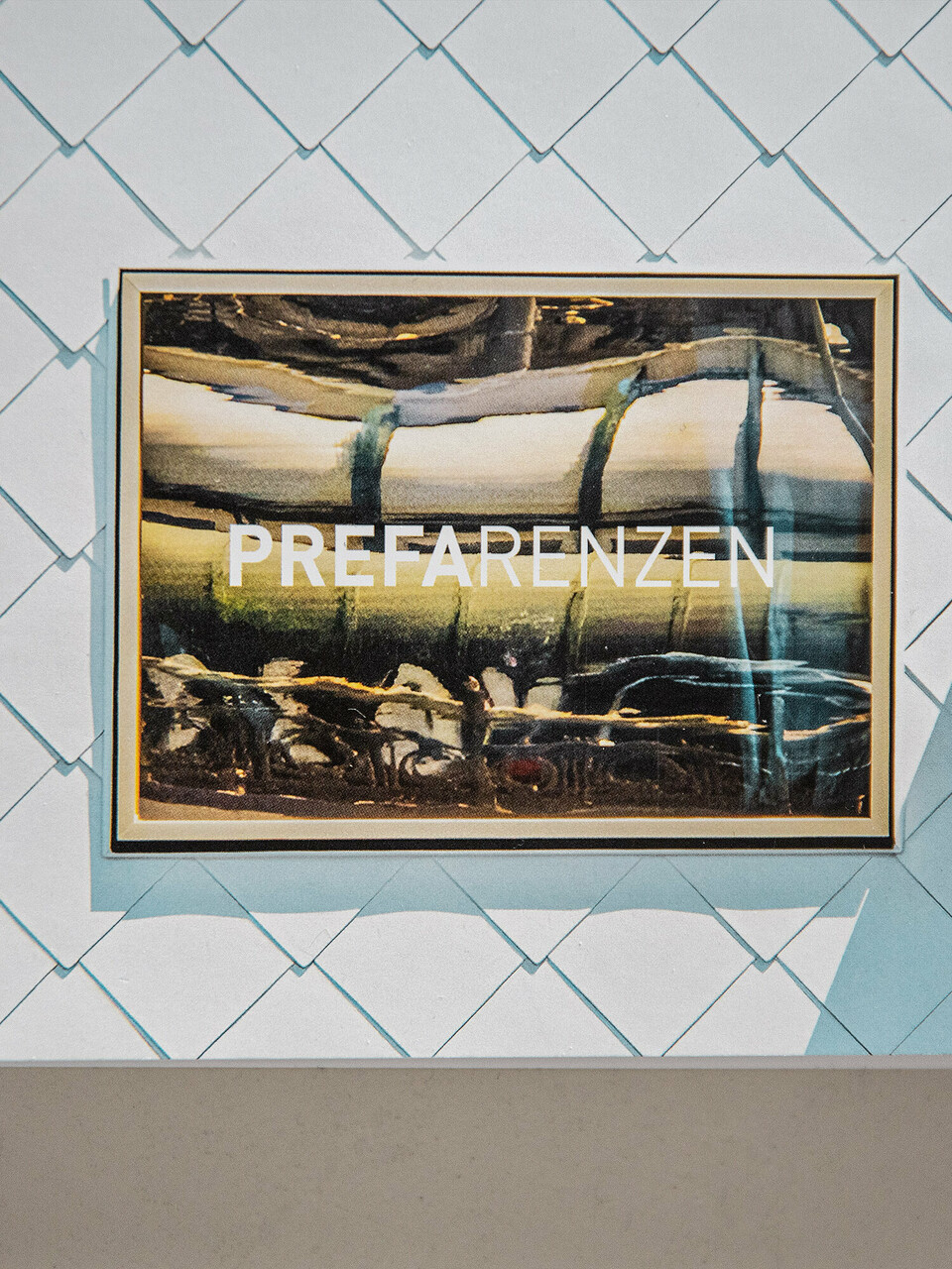 Photo rapprochée de l'angle du calendrier PREFARENZEN 2023. Un morceau de façade en losange blanc, THE ROCK Radisson RED Vienna Hotels, et une fenêtre réfléchissante dans les tons doux or, bronze et beige.