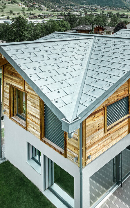 Chalet suisse avec une toiture en alu de PREFA. Le choix s’est porté sur la tuile R.16 couleur gris pierre. À l’étage supérieur, le choix s’est porté sur une façade en bois rustique.