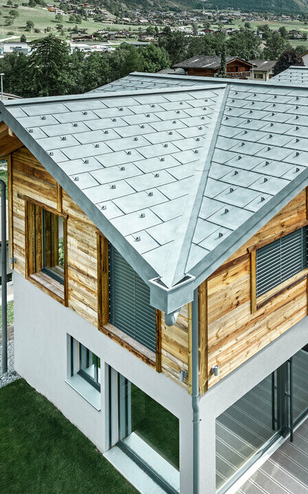 Chalet suisse avec une toiture en alu de PREFA. Le choix s’est porté sur la tuile R.16 couleur gris pierre. À l’étage supérieur, le choix s’est porté sur une façade en bois rustique.