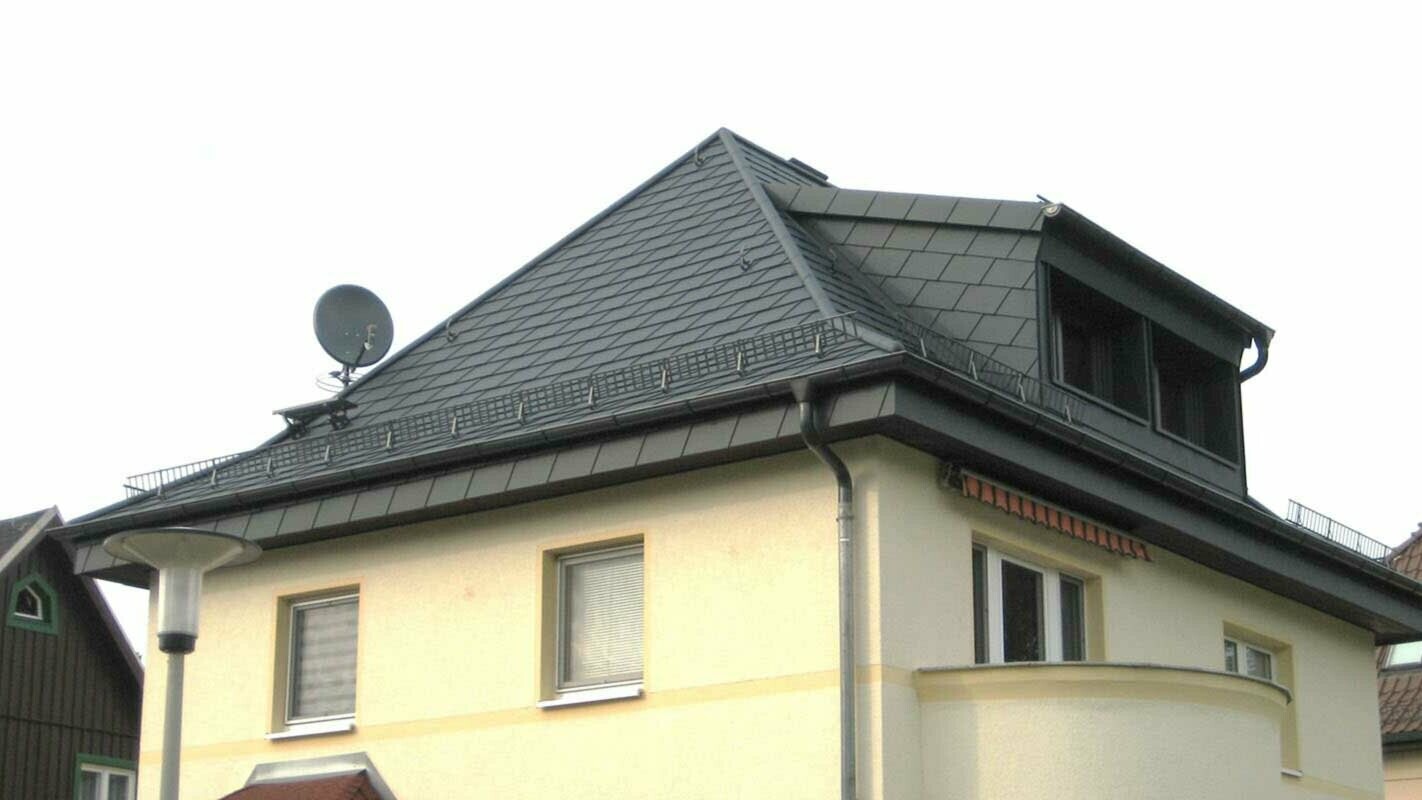 Rénovation de toit à croupes à l’aide de bardeaux de toiture PREFA et lucarne, façade jaune