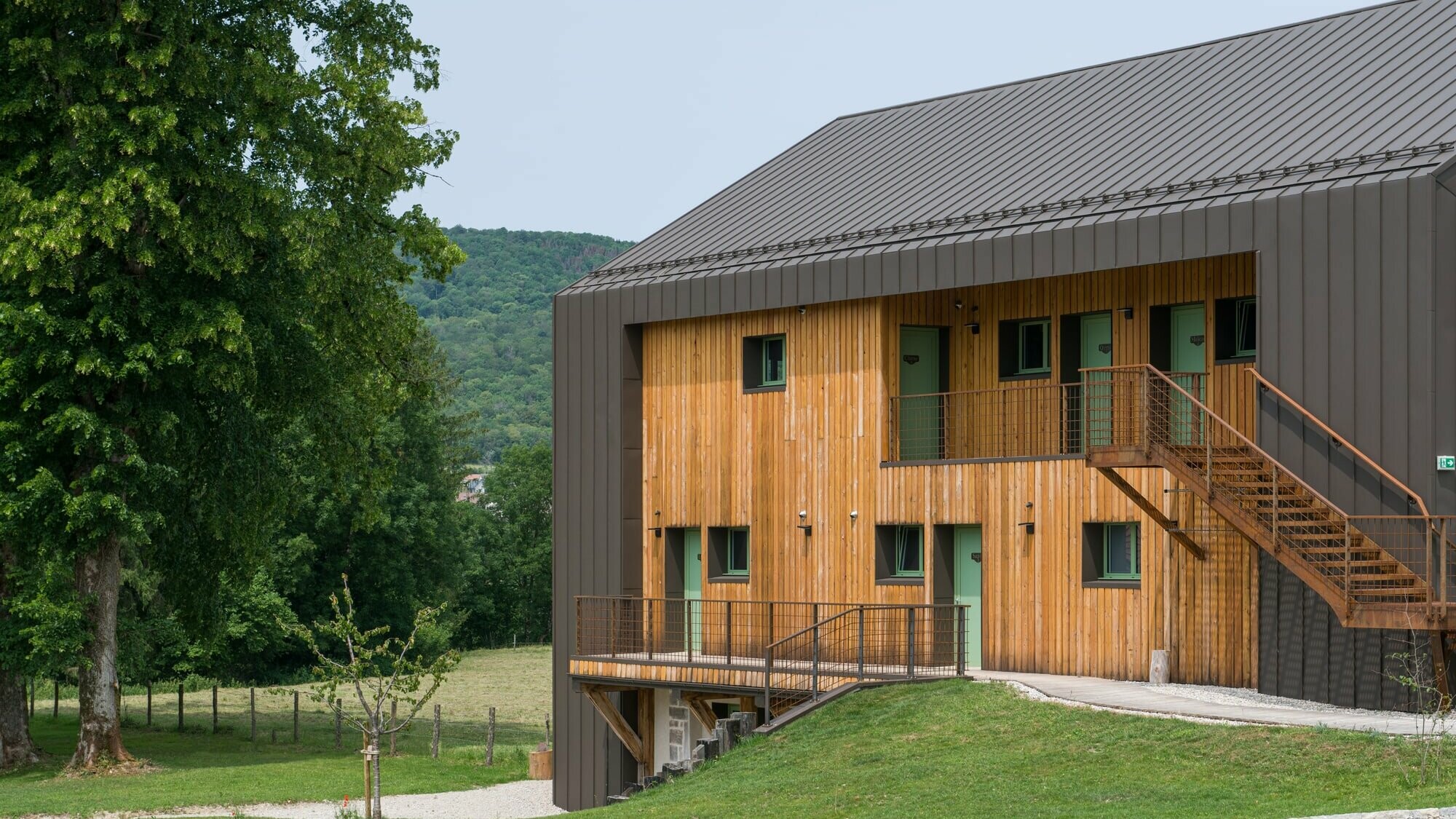 Vue du côté de l'hôtel en Tilleul : la façade et la toiture mélangent harmonieusement le bois et l'aluminium PREFA