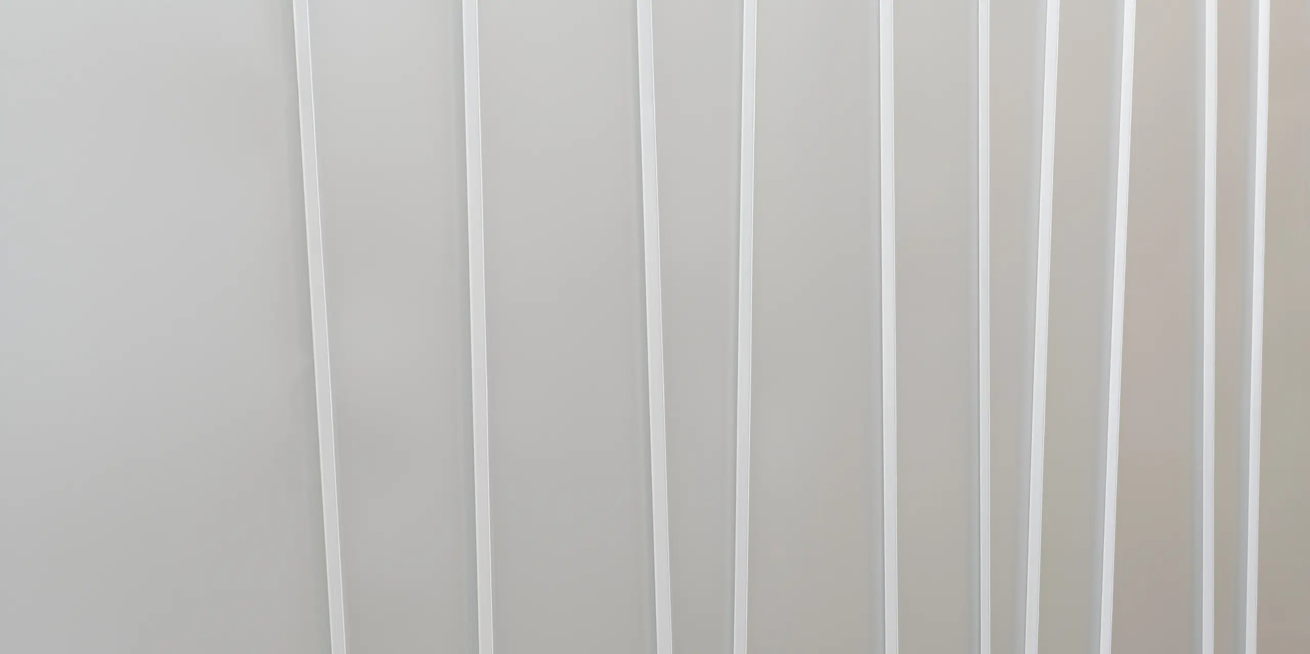 Gros plan d'un système de façade moderne en PREFALZ gris souris avec différentes largeurs de bacs. La texture épurée et minimaliste transmet une sensation d’ordre et un design contemporain.