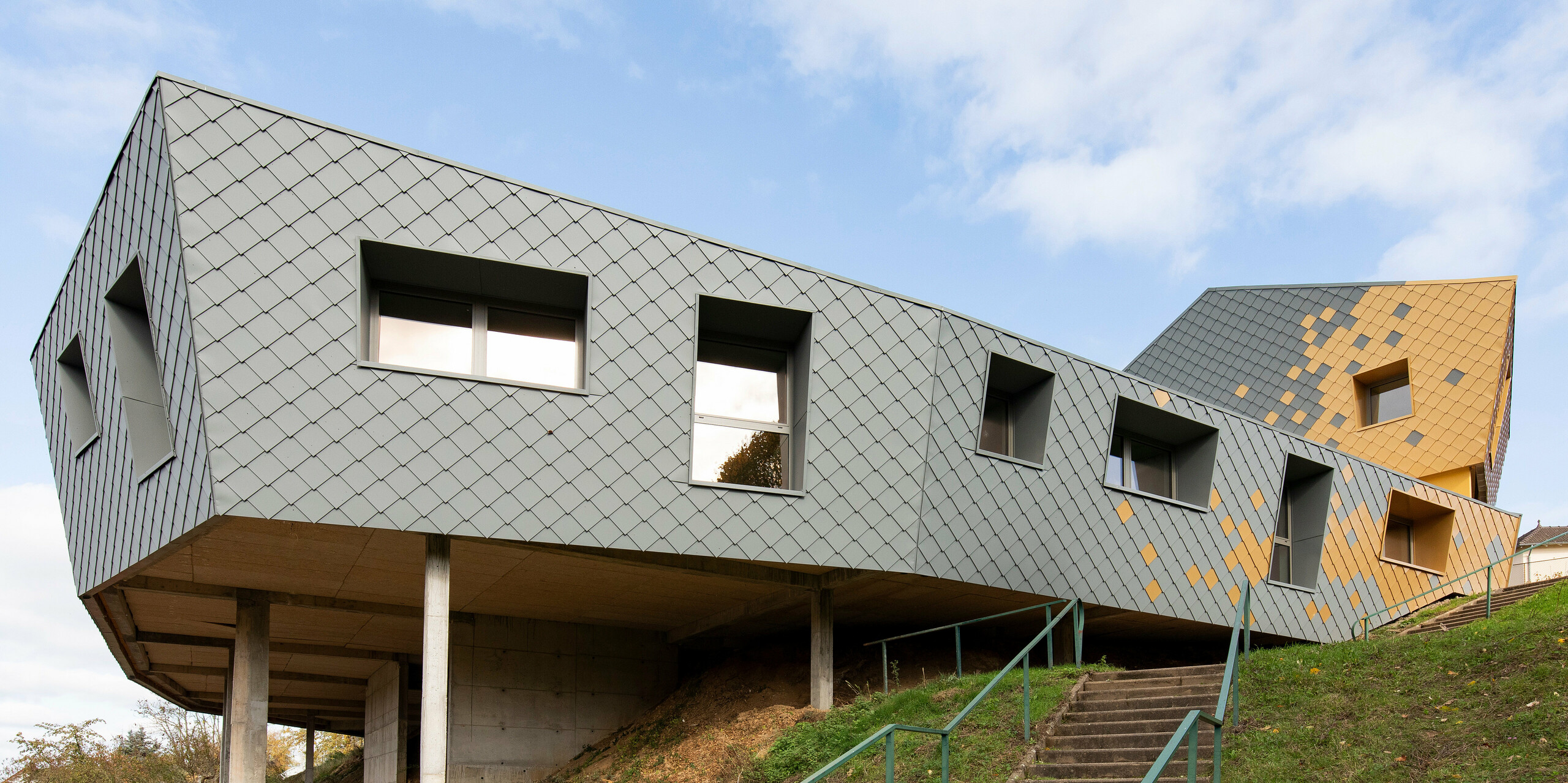 École primaire Jean Peyraud à Pierre-Buffière à flanc de colline avec une façade en losanges de façade PREFA 29×29 en gris souris P.10 et maya gold