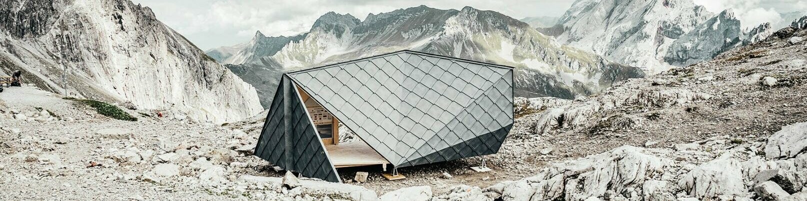 In der Mitte befindet sich die Hütte des Wisswak, die sich harmonisch in das Bergpanorama im Hintergrund einpflegt.