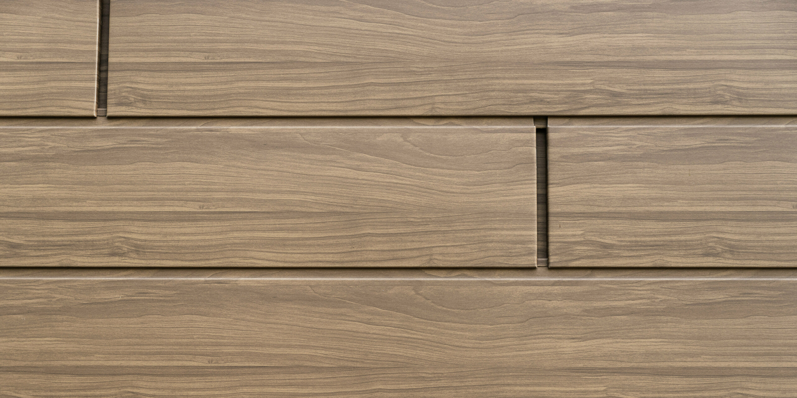 Vue détaillée des Sidings PREFA noyer foncé avec aspect bois authentique. Les panneaux de façade en aluminium durables combinent une esthétique naturelle avec une résistance aux intempéries et sans entretien.