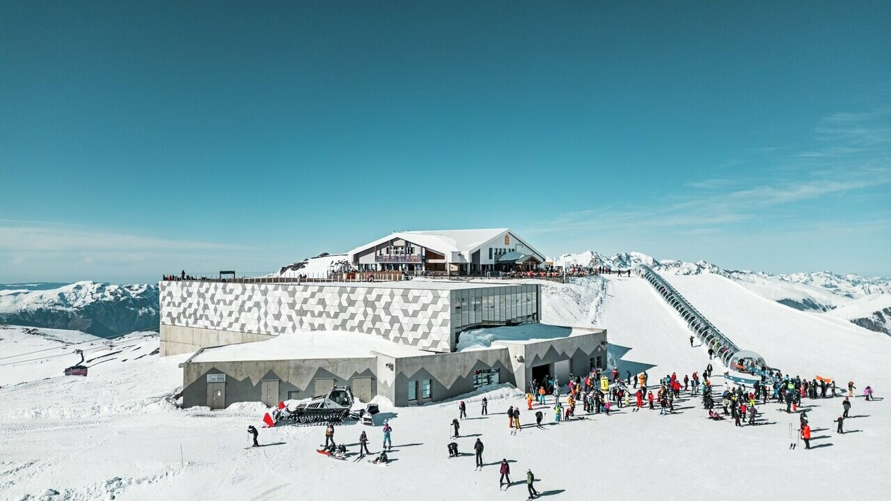 Vue éloignée d'une des stations d'altitude du nouveau téléphérique Le Jandri de la station Les 2 Alpes, recouverte de panneaux composites en aluminium PREFABOND façonné en losanges de trois couleurs différentes : blanc Prefa, blanc pur et argent fumé.