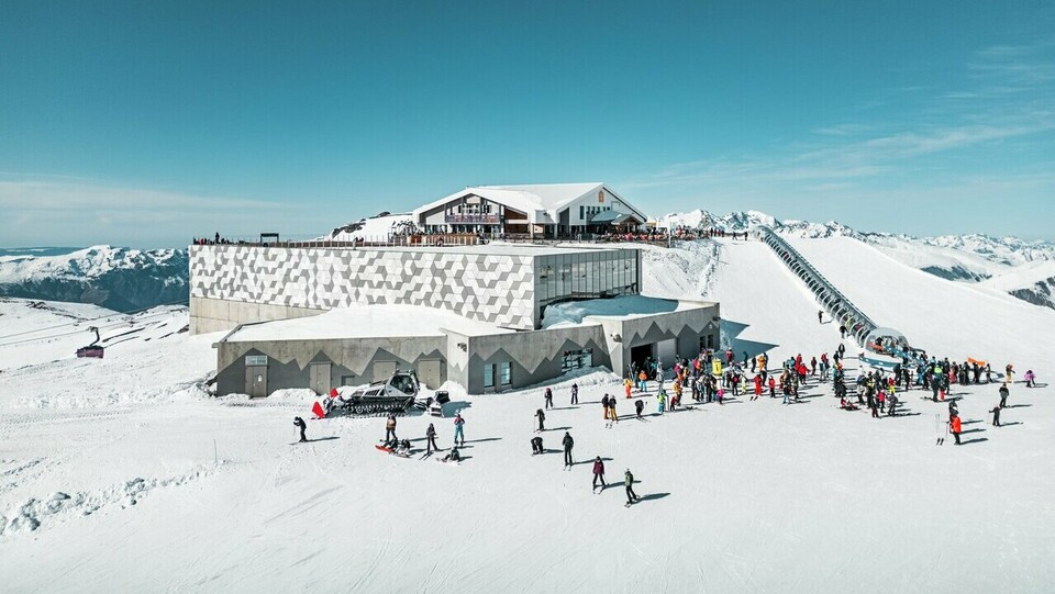 Vue éloignée d'une des stations d'altitude du nouveau téléphérique Le Jandri de la station Les 2 Alpes, recouverte de panneaux composites en aluminium PREFABOND façonné en losanges de trois couleurs différentes : blanc Prefa, blanc pur et argent fumé.