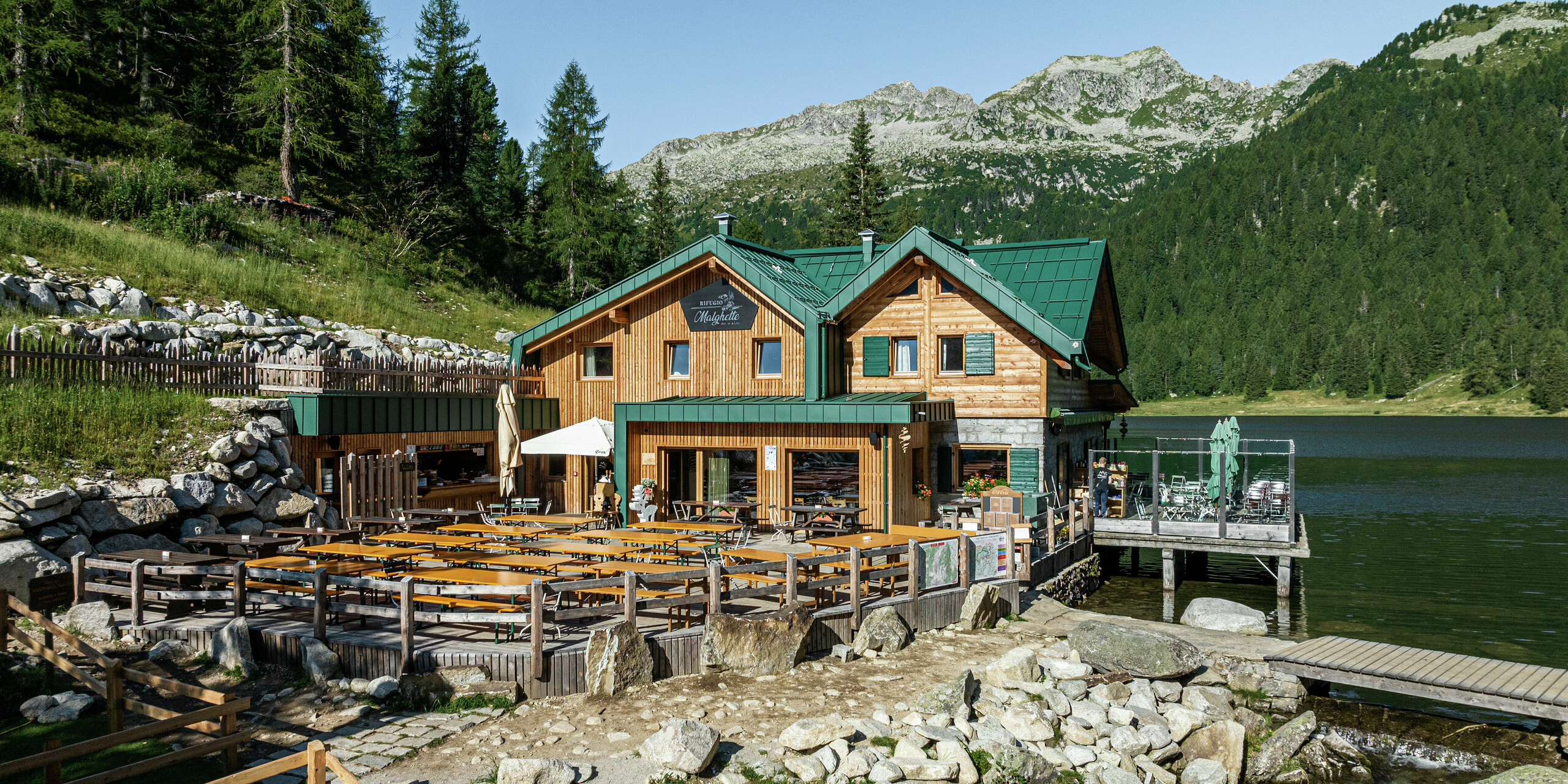 Le Rifugio Malghette à 1 888 m, situé directement sur le lac, avec un toit PREFALZ résistant aux intempéries en vert mousse P.10. Le toit en aluminium durable protège la cabane des conditions météorologiques extrêmes et s'intègre parfaitement dans le paysage alpin. La spacieuse terrasse ensoleillée offre une vue unique sur les montagnes environnantes.