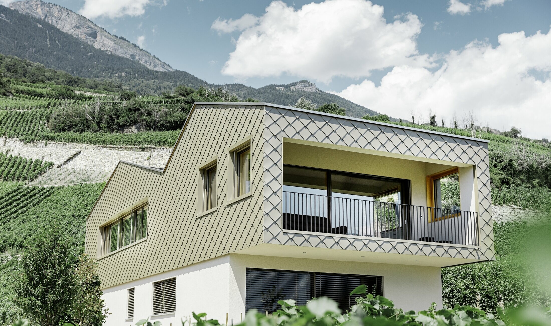 Maison individuelle moderne au cœur des vignobles de la vallée du Rhône avec quatre pentes de toit et grand balcon couvert — Façade habillée de losanges PREFA de couleur bronze