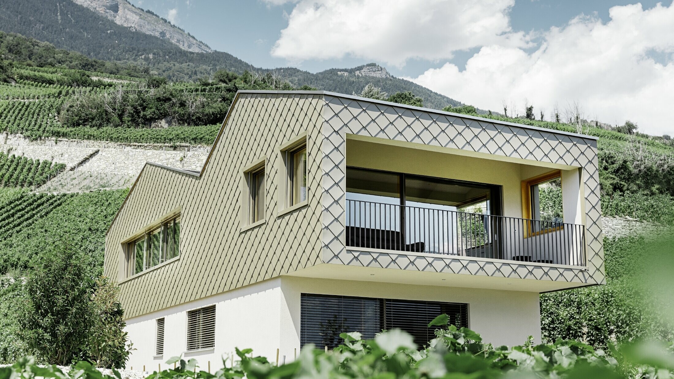 Maison individuelle moderne au cœur des vignobles de la vallée du Rhône avec quatre pentes de toit et grand balcon couvert — Façade habillée de losanges PREFA de couleur bronze